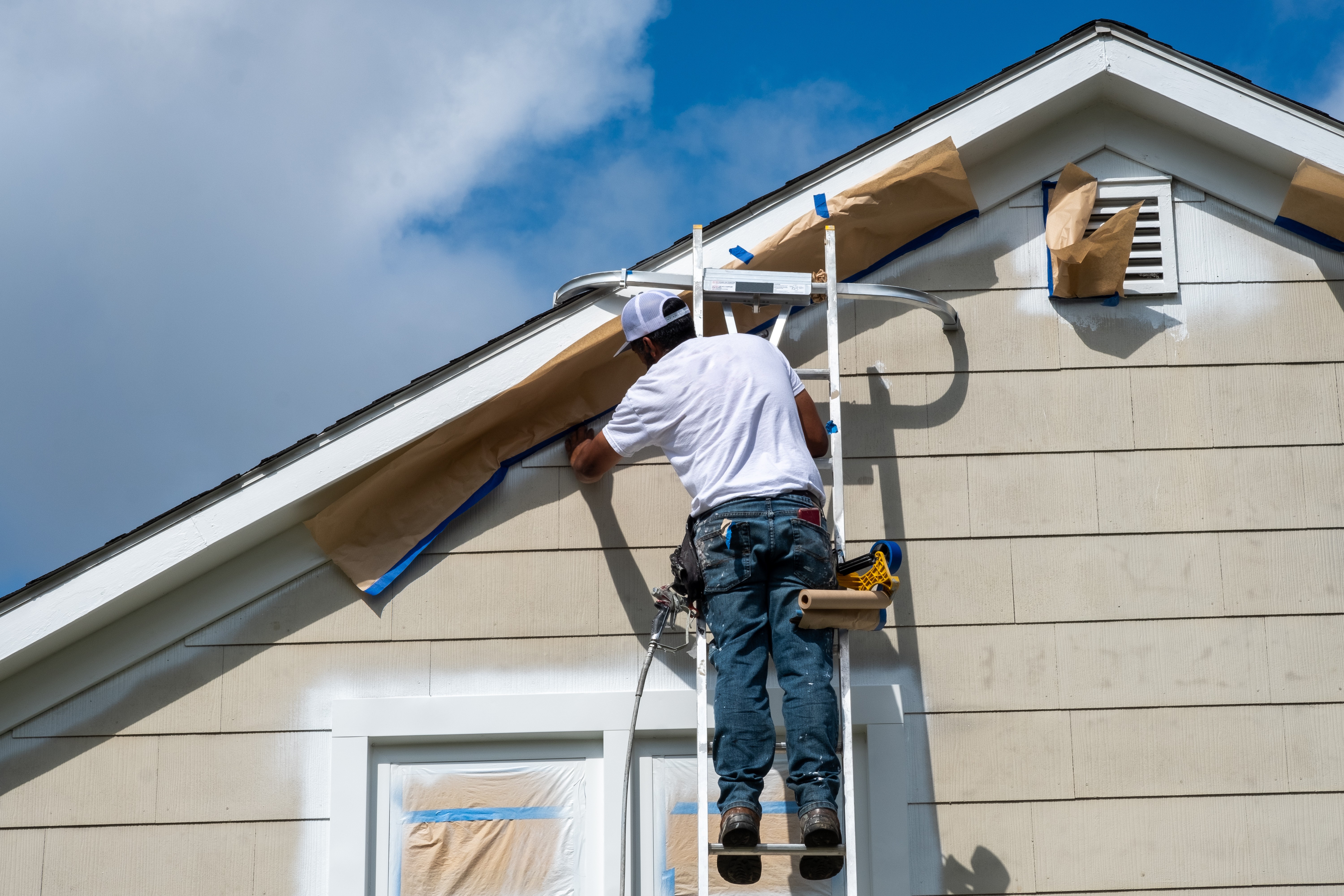 Roofer installing shingles on a roof at sunset.