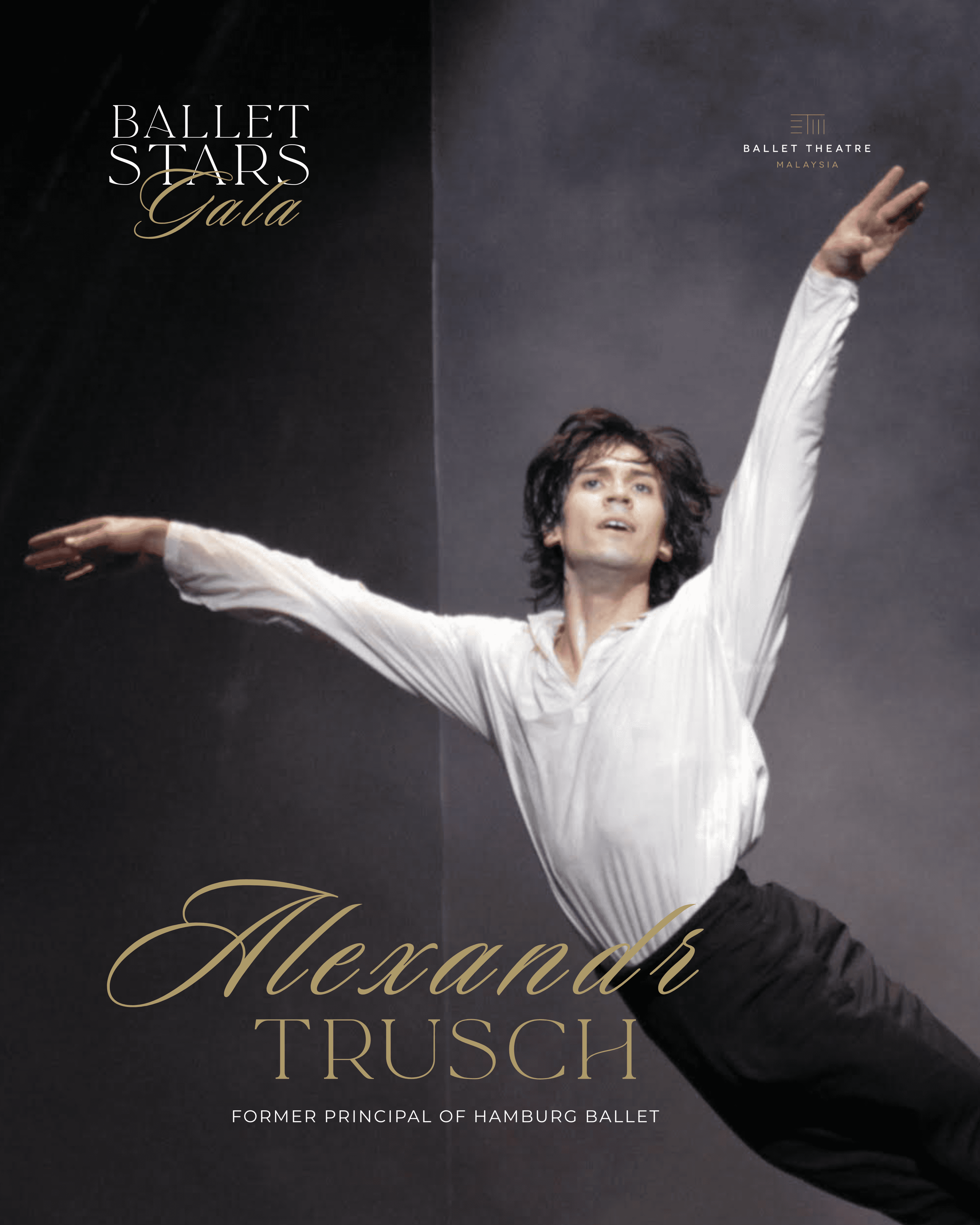 A male ballet dancer in mid-leap, wearing a white shirt and black pants, performing on stage under dramatic lighting.