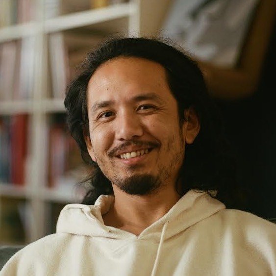 A smiling woman writing on a piece of paper in her home