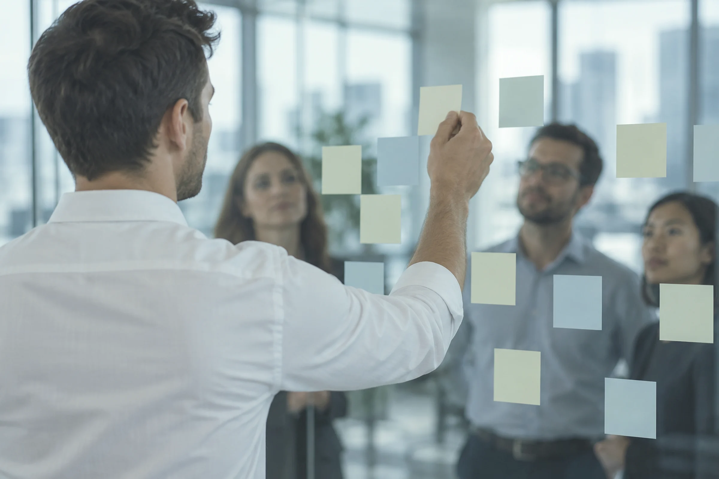 A consultant placing a sticky note on a glass wall