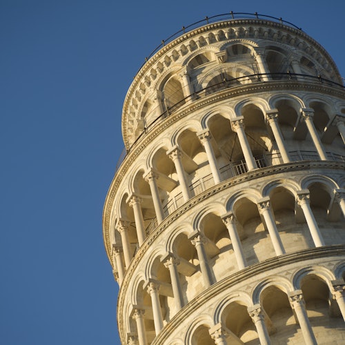 Close-up of the upper portion of the Leaning Tower of Pisa against a clear blue sky.