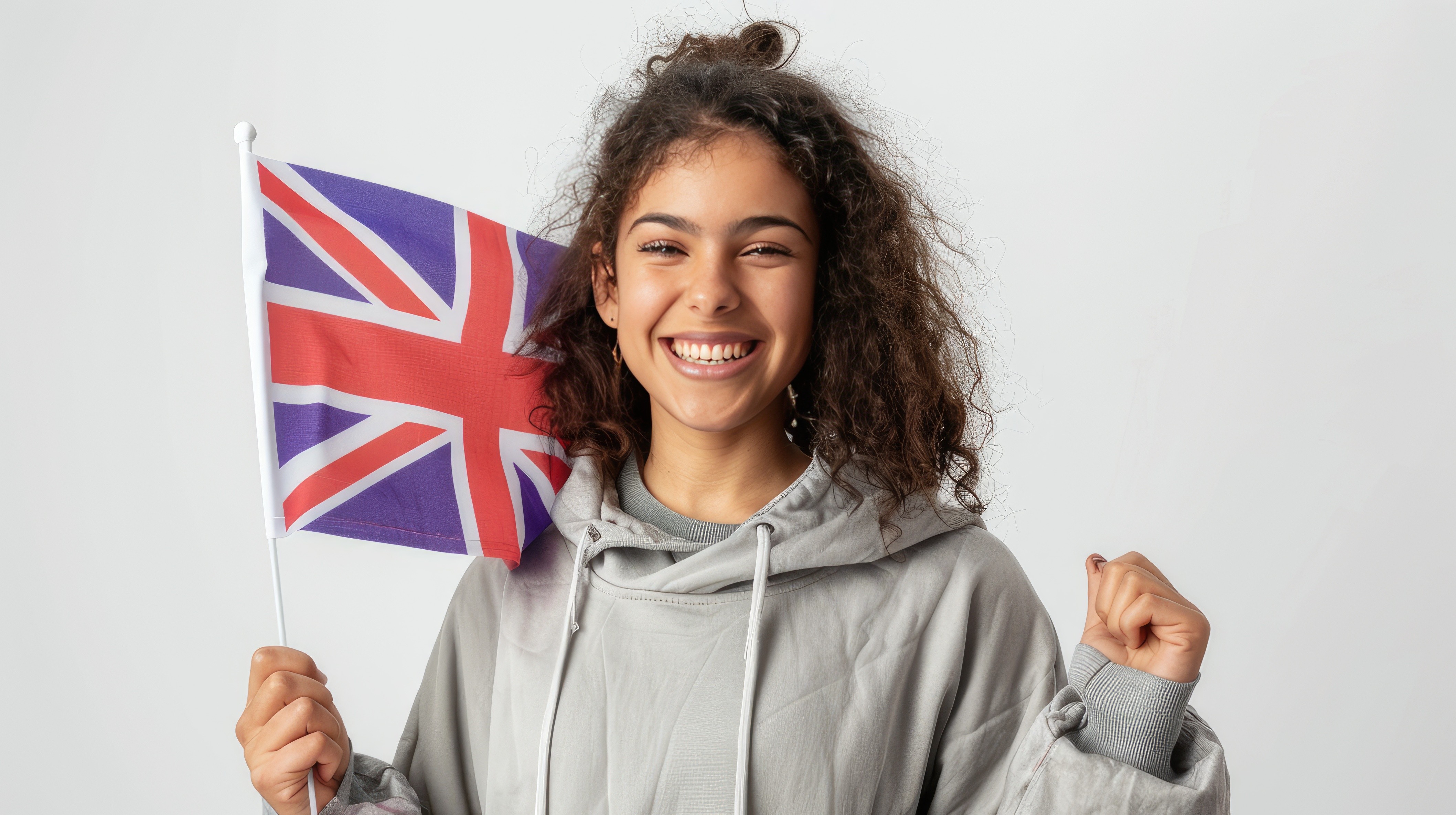 A cheerful young Latin woman proudly holds the English flag expressing patriotism and admiration isolated on a white background