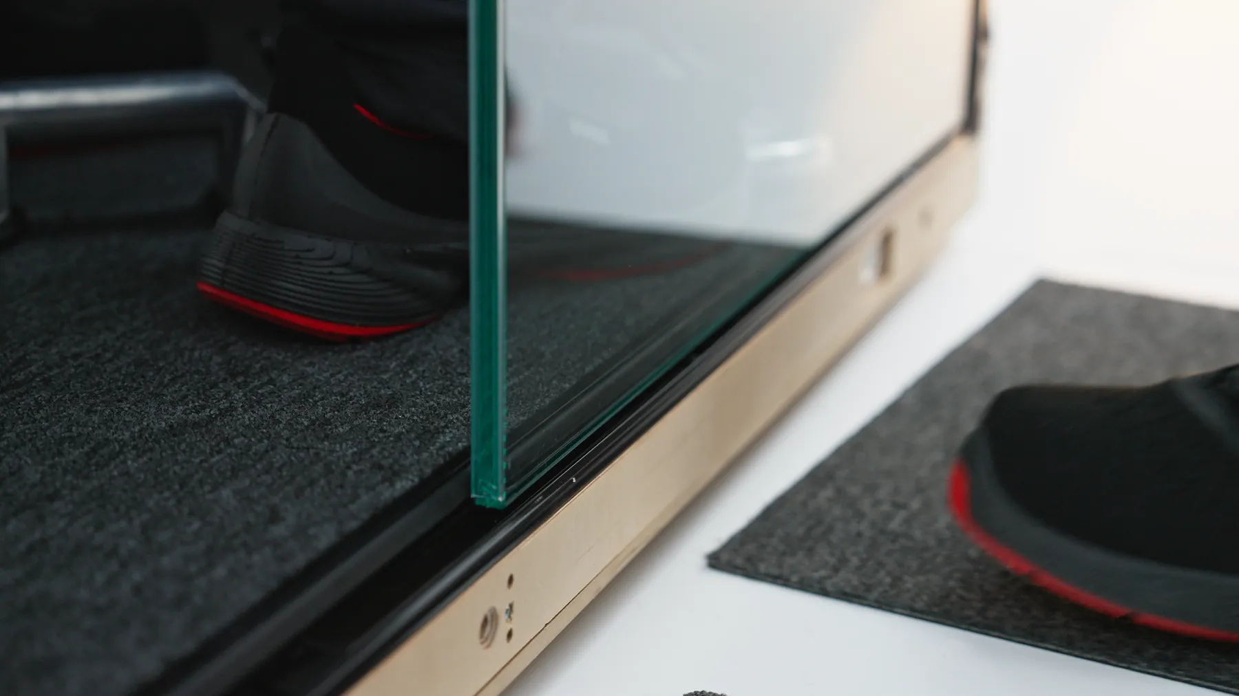 Close-up of a glass door seam and floor track on a Silen pod