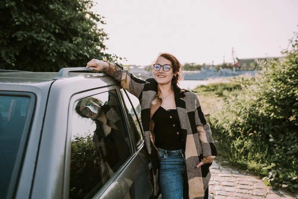 Gründerin Julia Fischer an einem Auto Strahlend