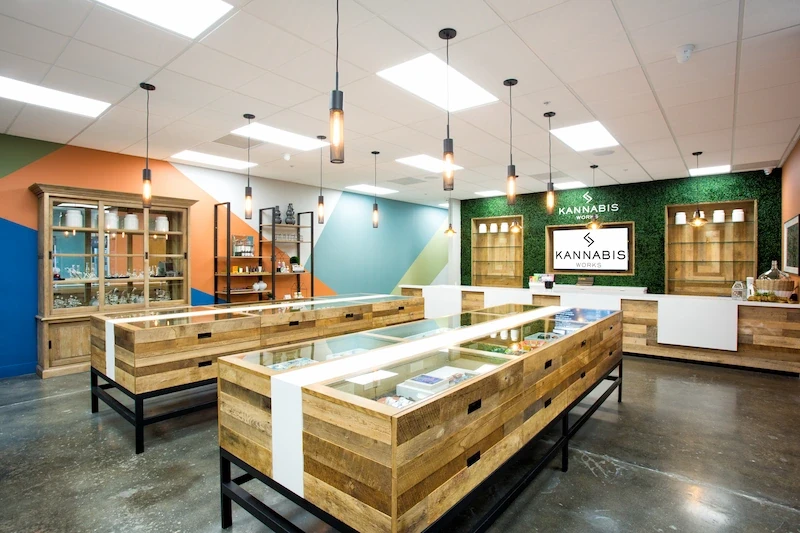 Vibrant Kannabis Works shop interior with colorful walls, wooden display tables, and pendant lights.