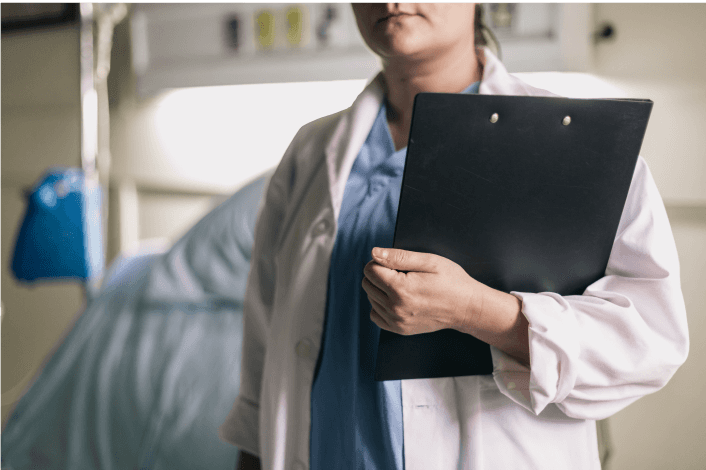 Doctor holding a clipboard in a hospital room.
