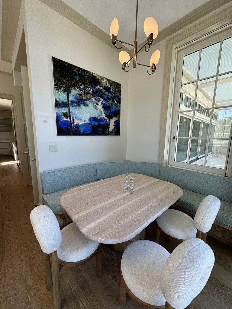 Framed coastal landscape painting above a breakfast nook banquette