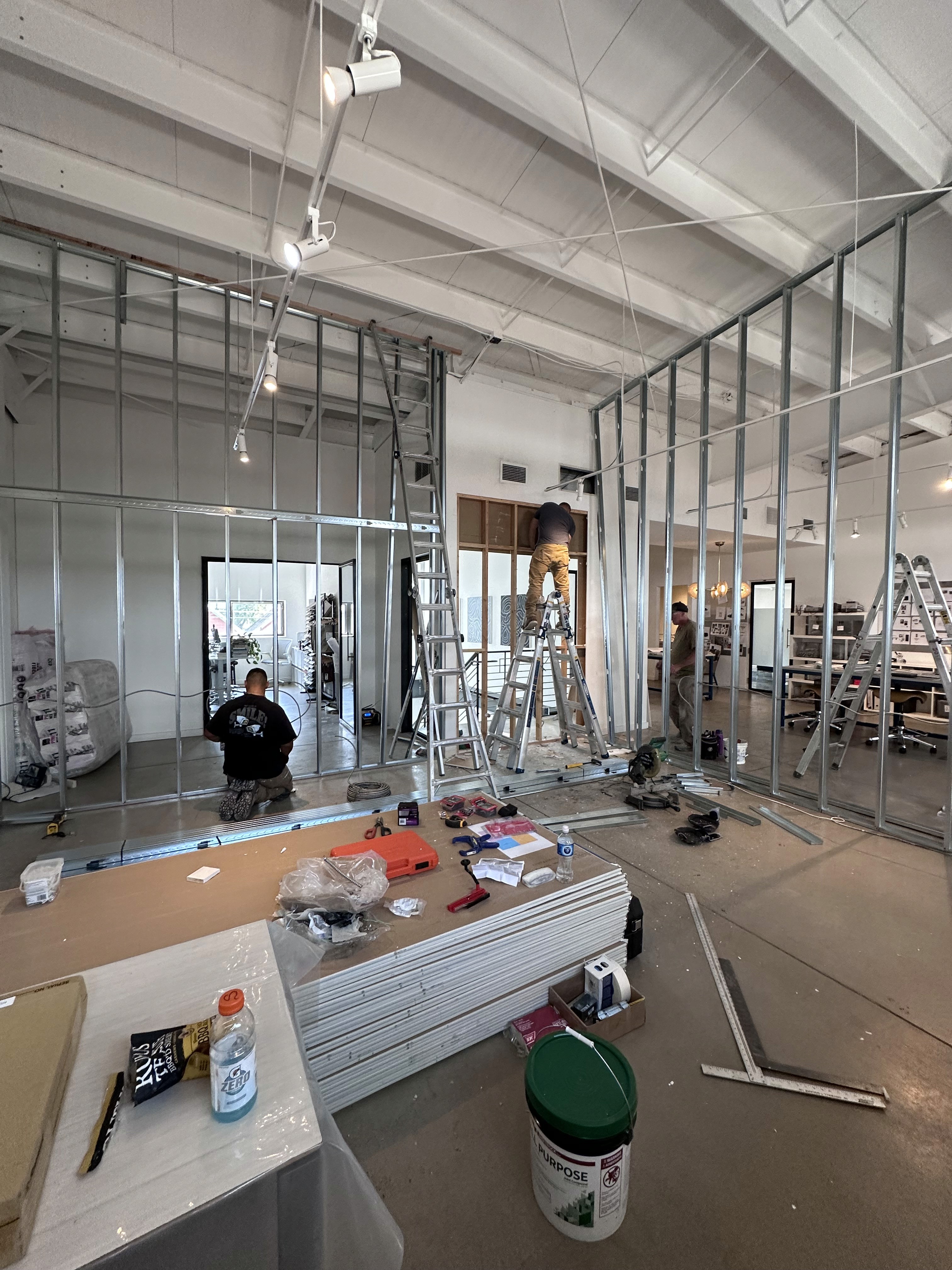Newly installed drywall and framing in a commercial interior renovation with high ceilings and exposed structural beams.