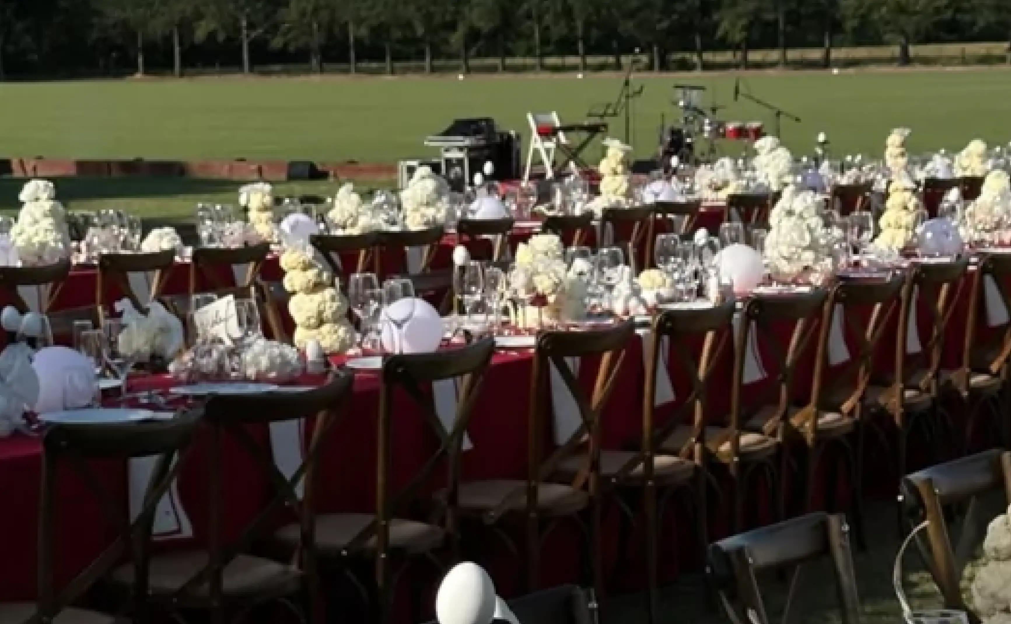 Vista general de mesas alineadas con decoración blanca y manteles rojos para eventos de lujo que integran estilo contemporáneo y simetría natural.