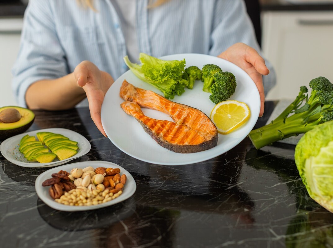 woman showing off a healthy meal of salmon and vegetables to support her number of steps for weight loss