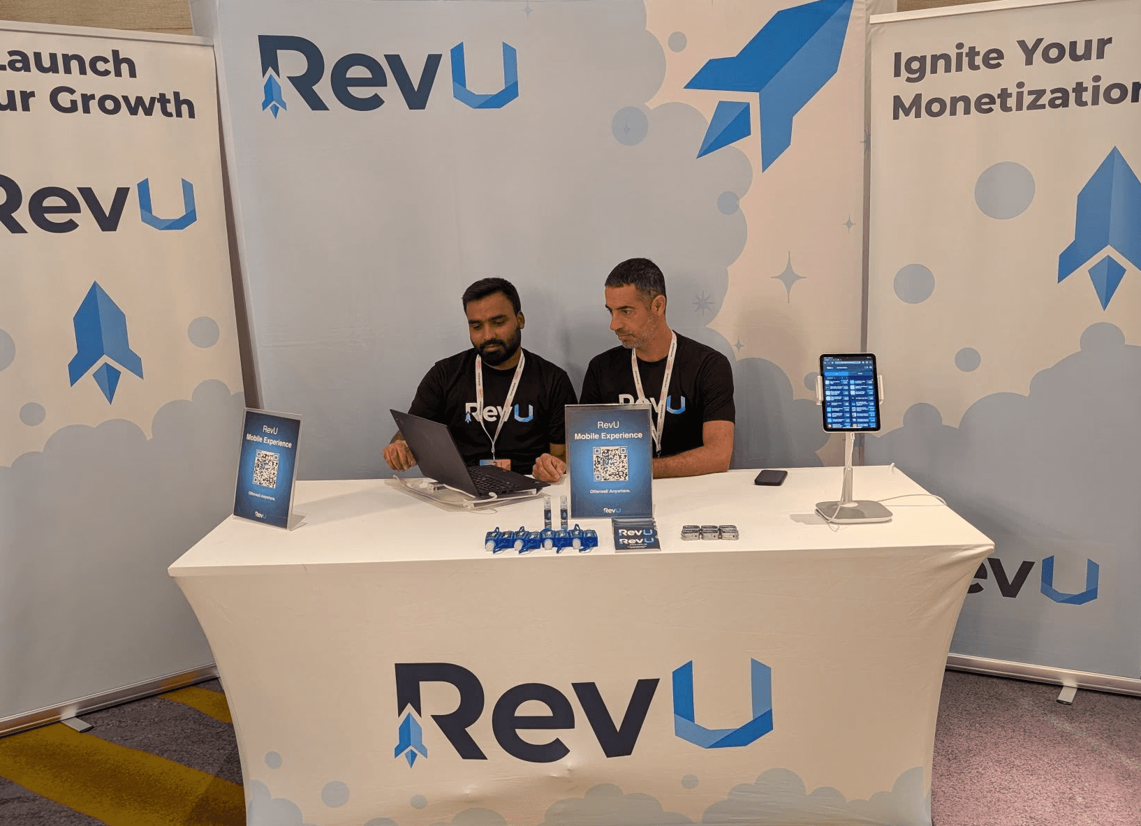 Two men in RevU shirts at their branded exhibition booth.