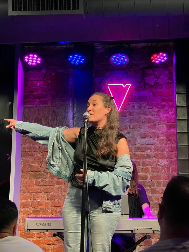 A performer reaches out toward the audience mid-song