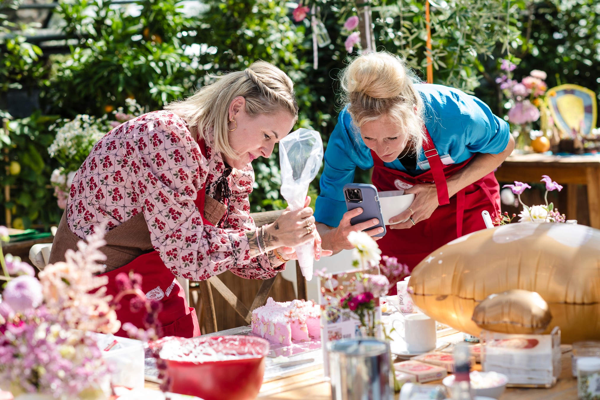 Zwei Frauen dekorieren eine Torte mit Spritzbeutel bei einem Backworkshop