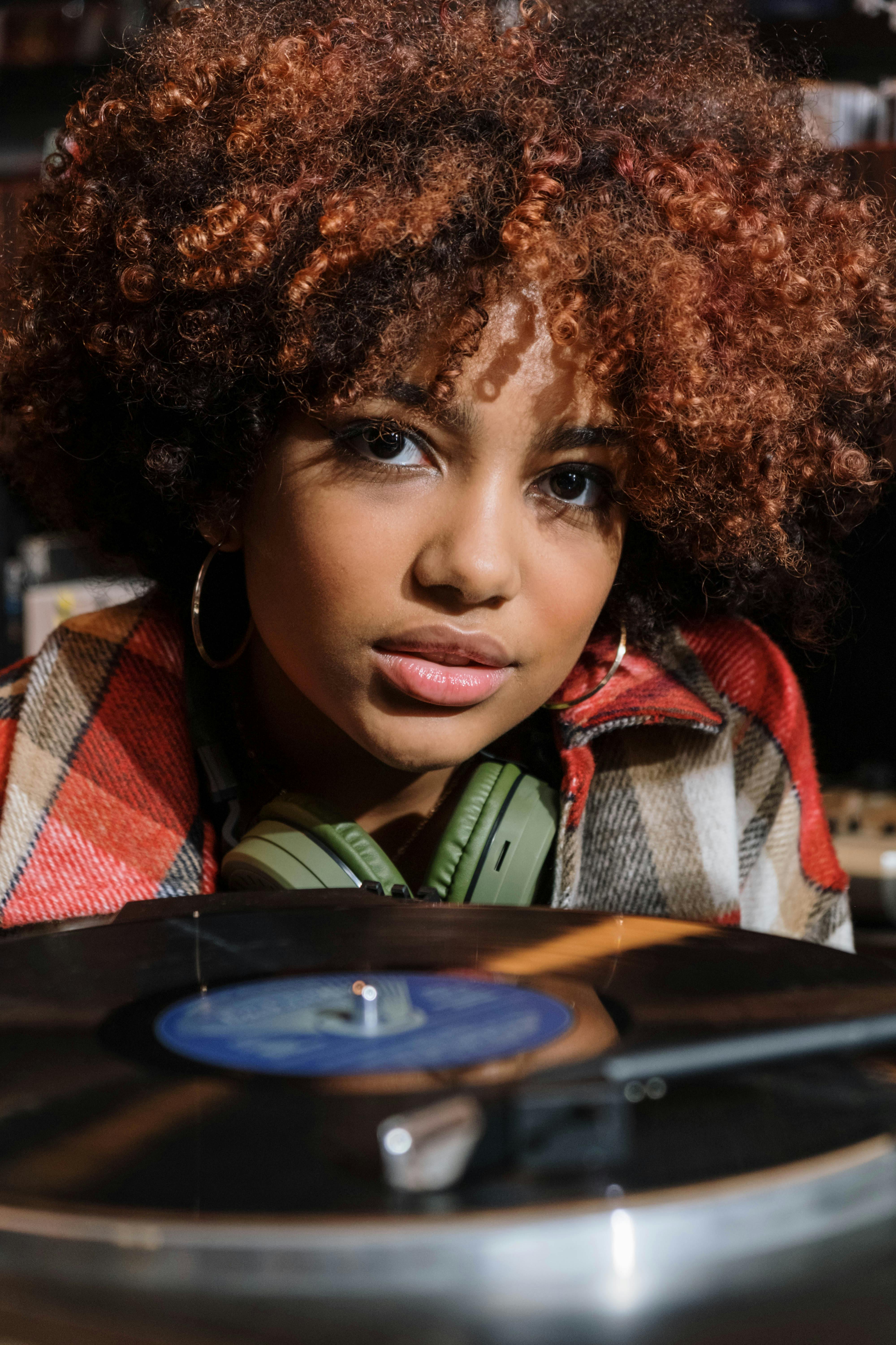 Person listening near turntable with curly hair