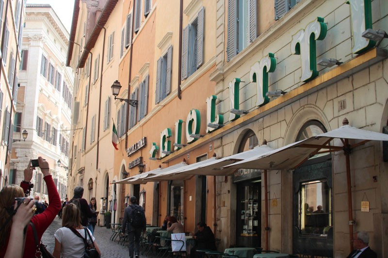 A photo of a narrow street between orange and white buildings and on one of them the text: Giolitt.