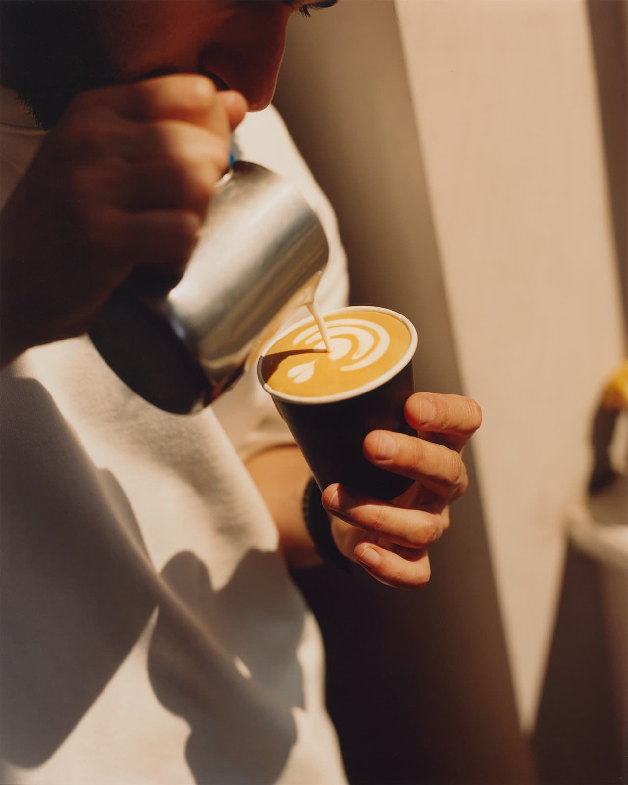 A barista pooring a coffee cup inside an NKORA Coffee Shop