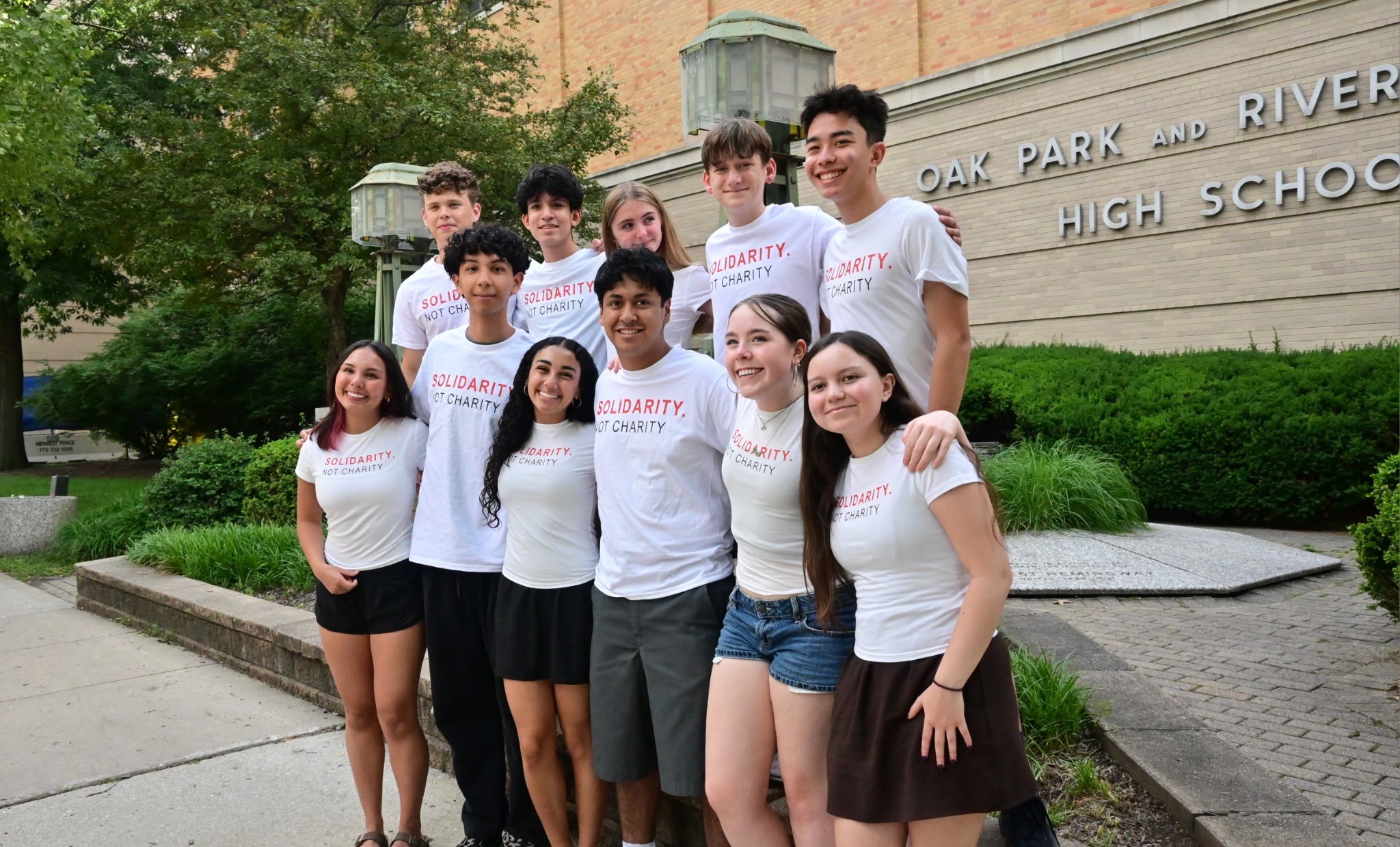 Group of students in Solidary, Not Charity t-shirts standing outside OPRF high school