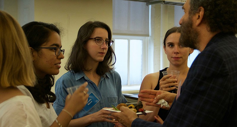 A photo of a group of people sitting in an office room and talking.
