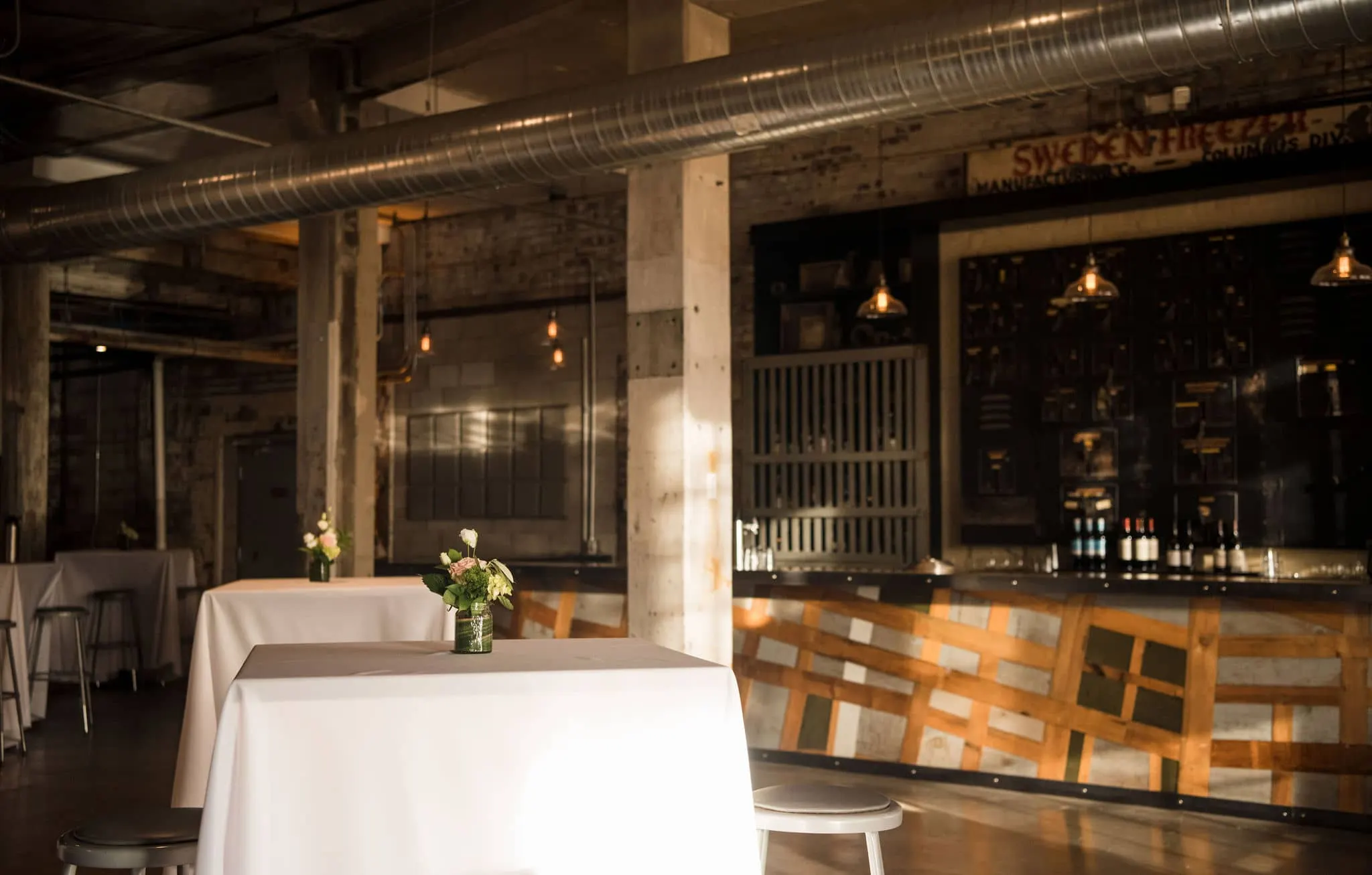 Bar and cocktail tables with white linens inside Strongwater