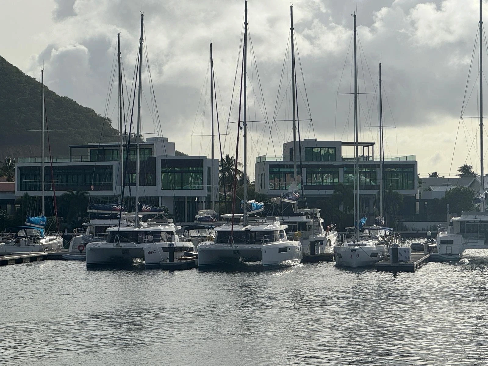 Sailboat masts framing the modern white Rodney Bay residences in St. Lucia designed by Atelier International, seen from across the marina.