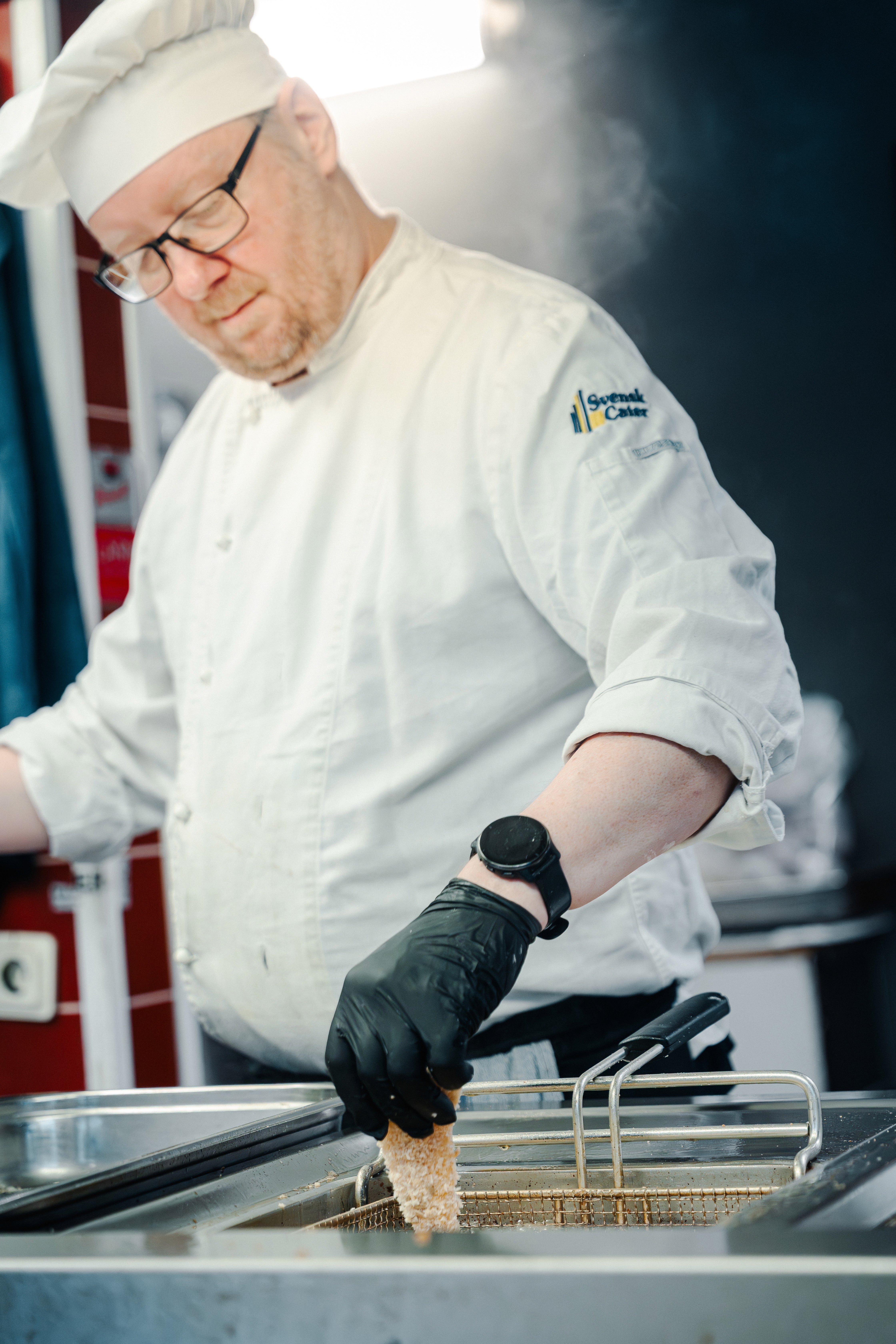 Man eats salad at a table indoors.