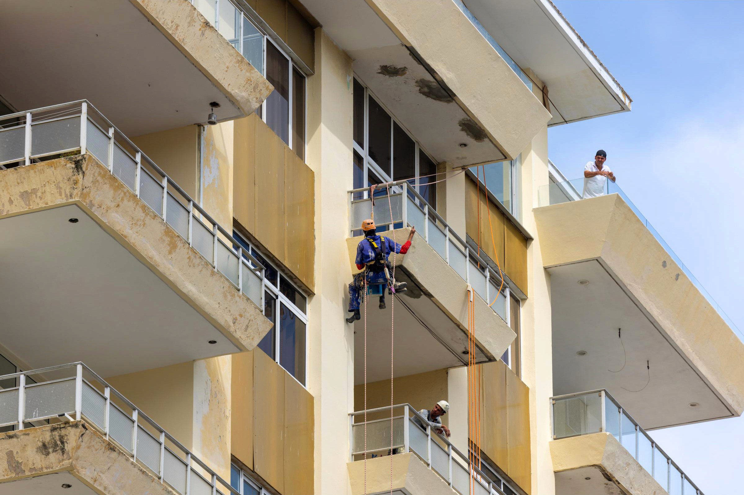 Construction worker rappels the side of a large residential building - Havana, Cuba