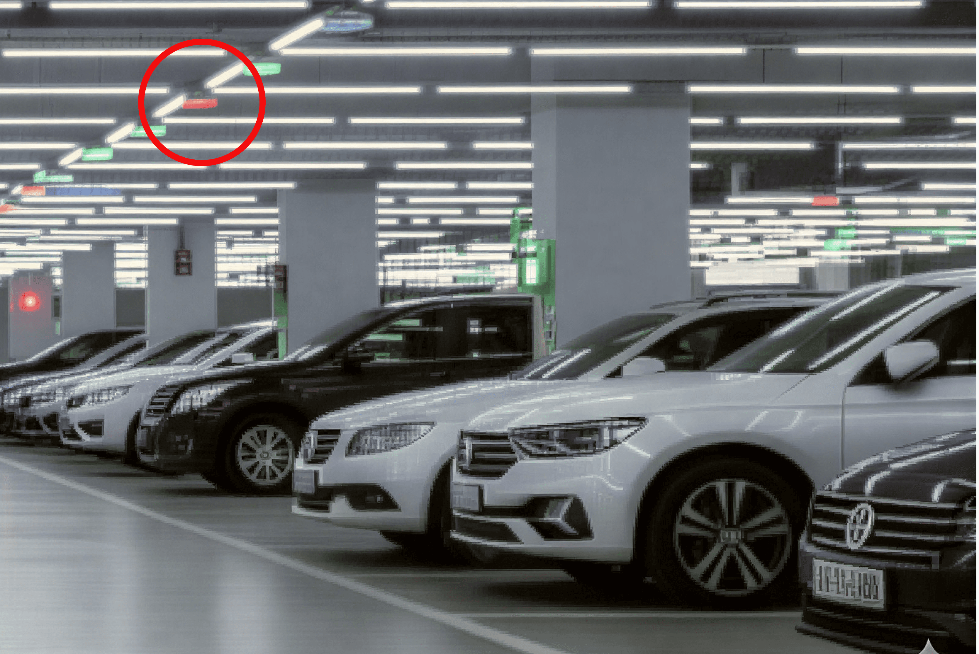 차량이 주차된 실내 주차장 천장에 설치된 주차 유도 카메라를 빨간 원으로 표시한 사진입니다.