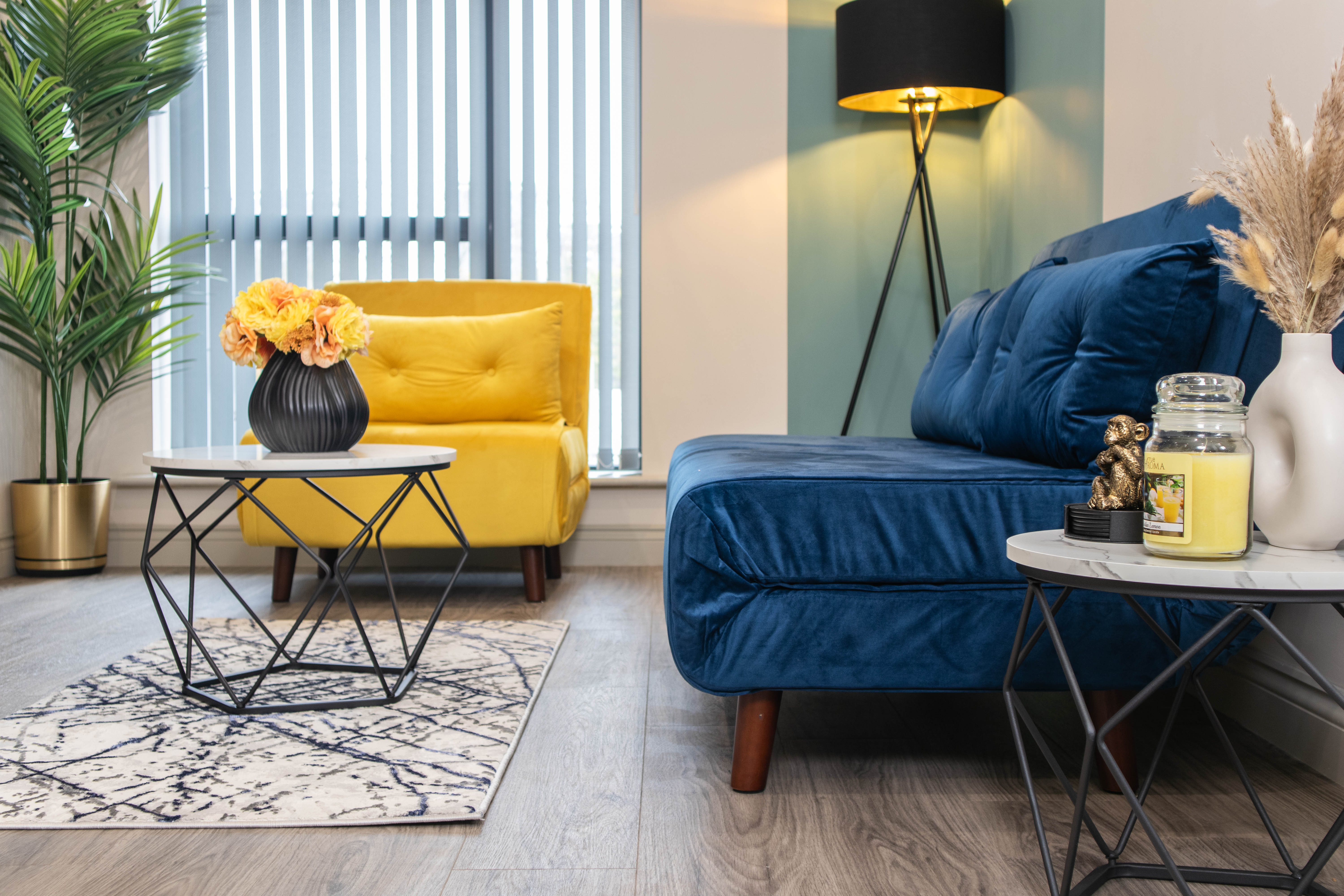 Colourful Airbnb with blue couch and yellow accent chair with geometric coffee table