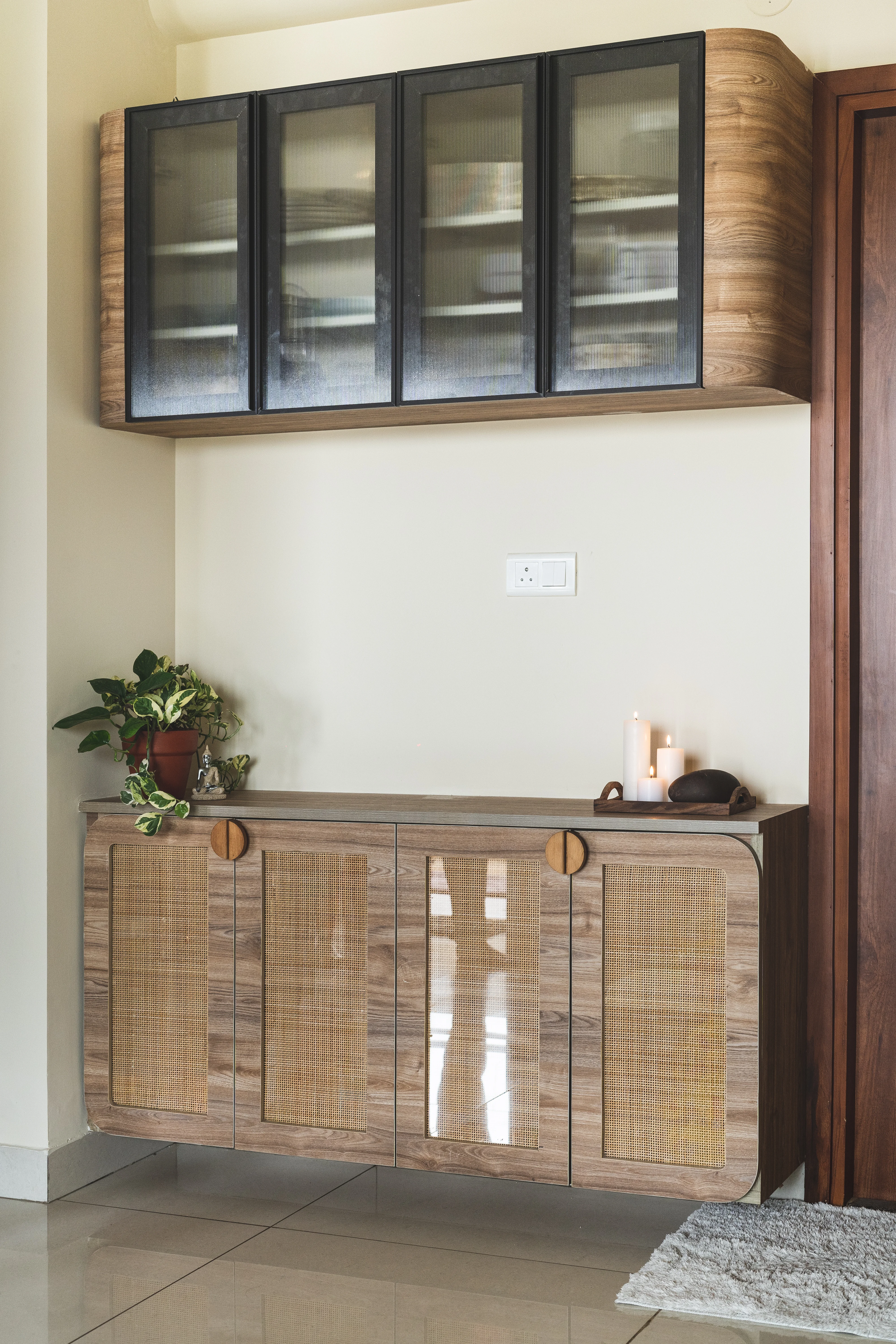 A wooden cabinet with glass doors displaying a plant, highlighting minimalistic design for South Indian interiors.