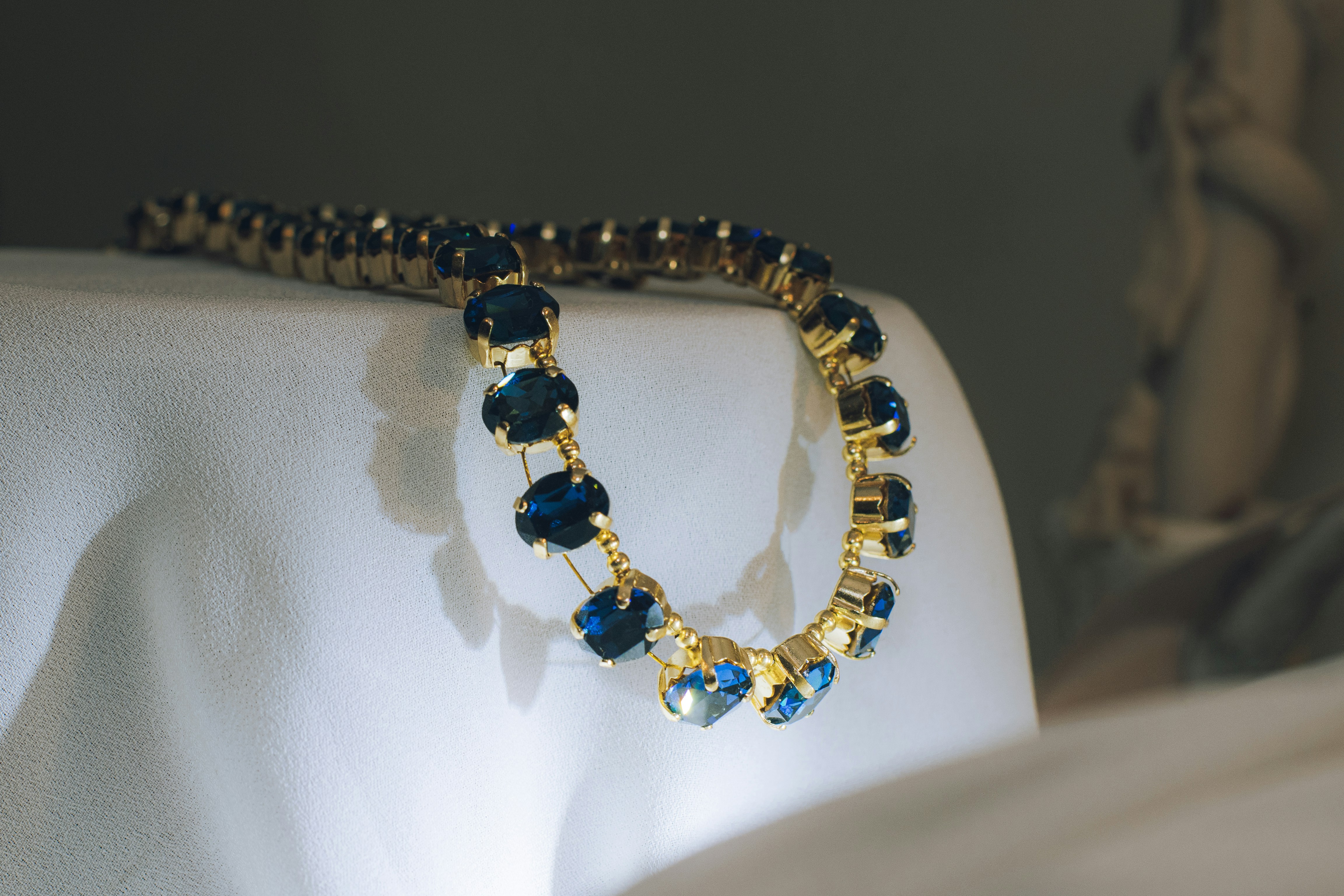 Gold necklace with blue gemstones on white fabric