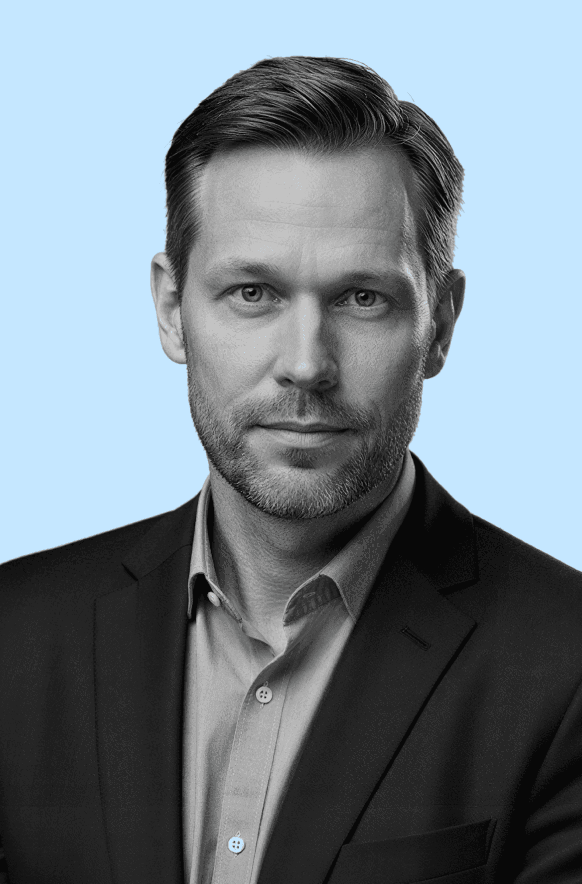 A black and white photo of a man wearing a suit, standing confidently with a serious expression.