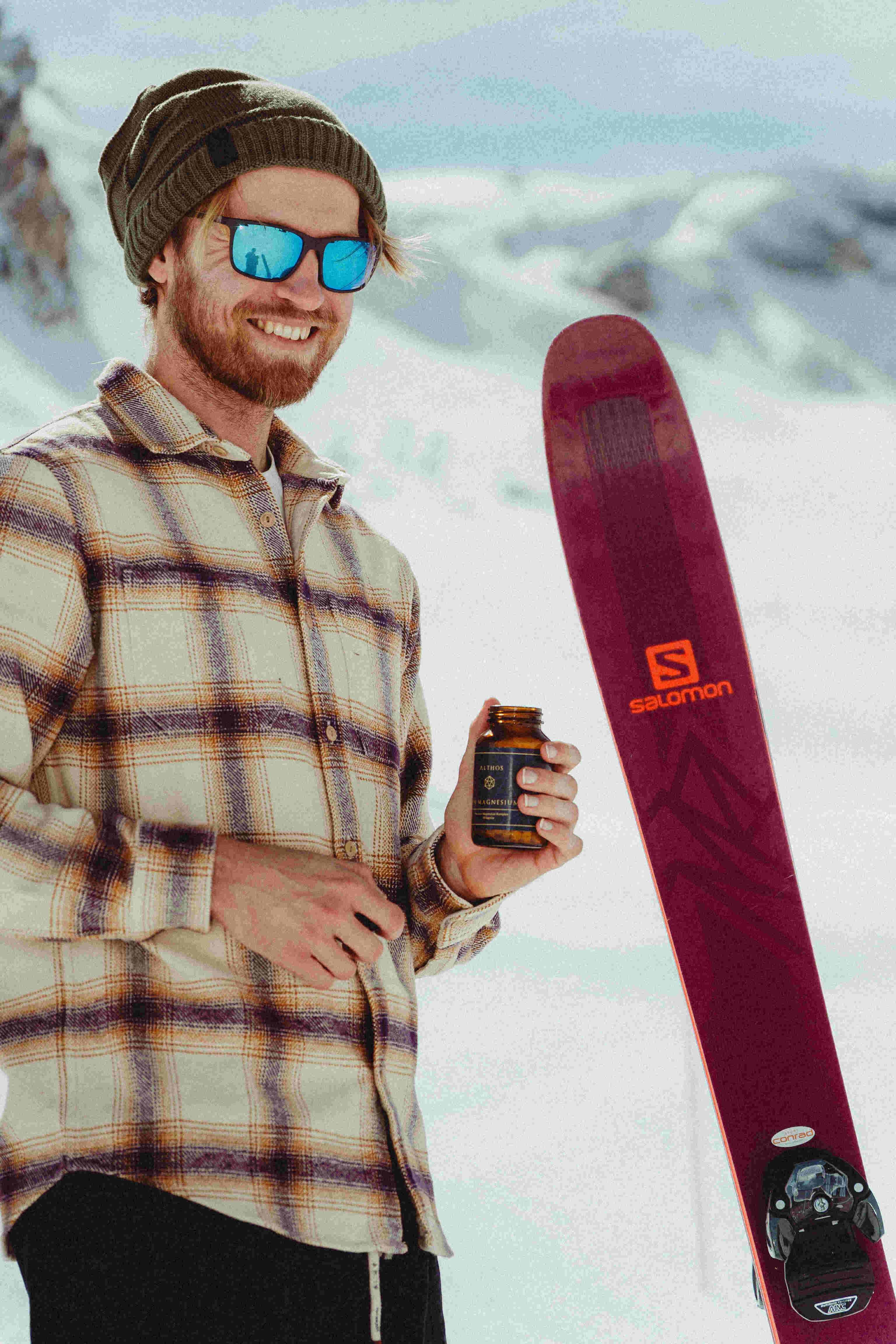 High-angle shot of a sprinter in a black outfit and bright yellow cap running on a red track.