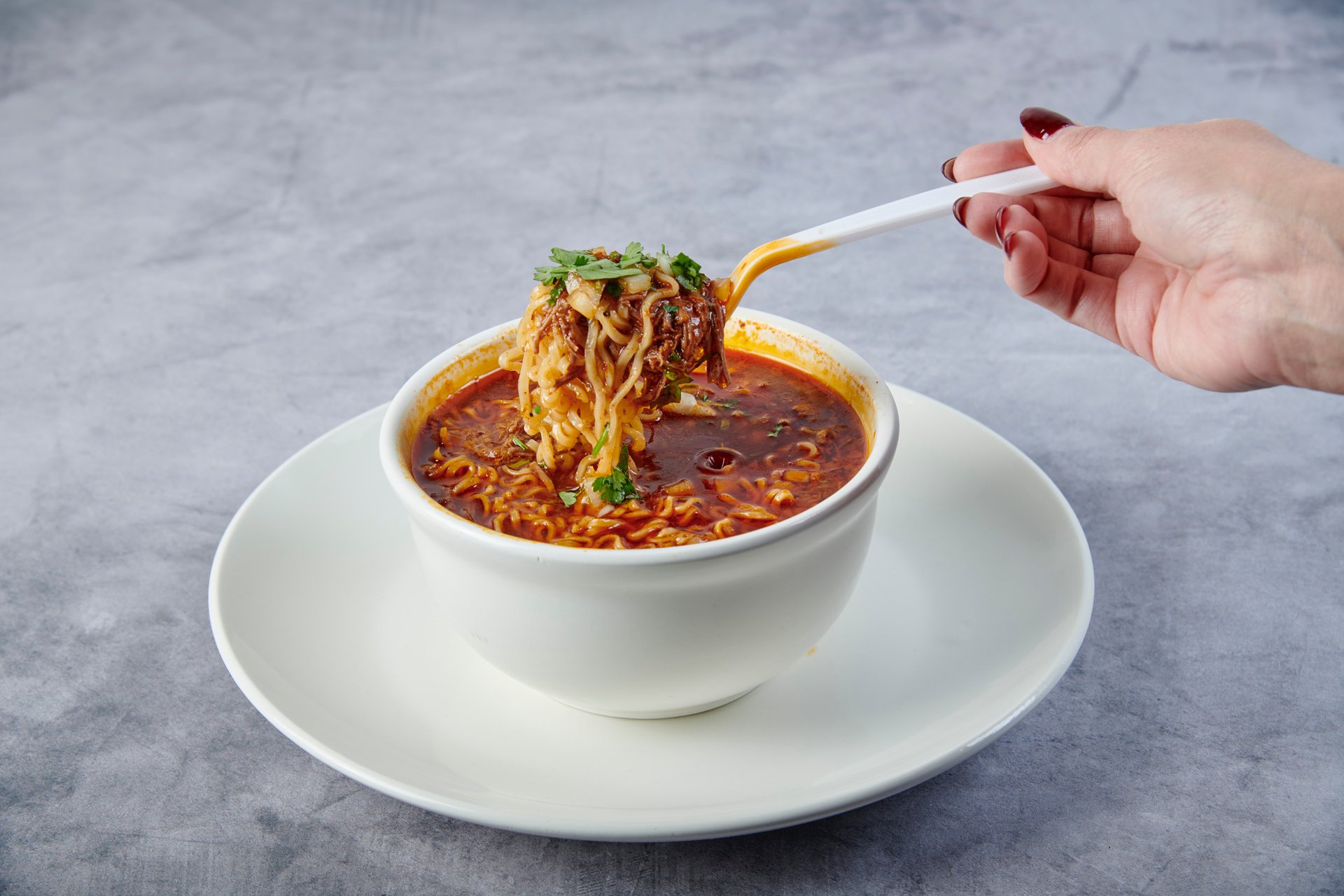 Birria Ramen at Fuego Cravings - A hearty bowl of noodles in flavorful birria broth, topped with fresh cilantro, onions, and lime.