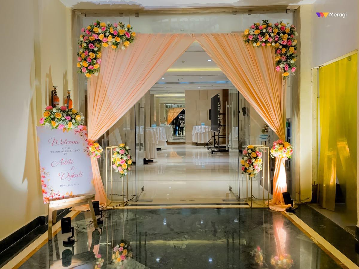 Indoor wedding entrance with peach drapes & pastel flowers in Dwarka, Palam, Janakpuri, South Delhi, Timarpur & Malviya Nagar