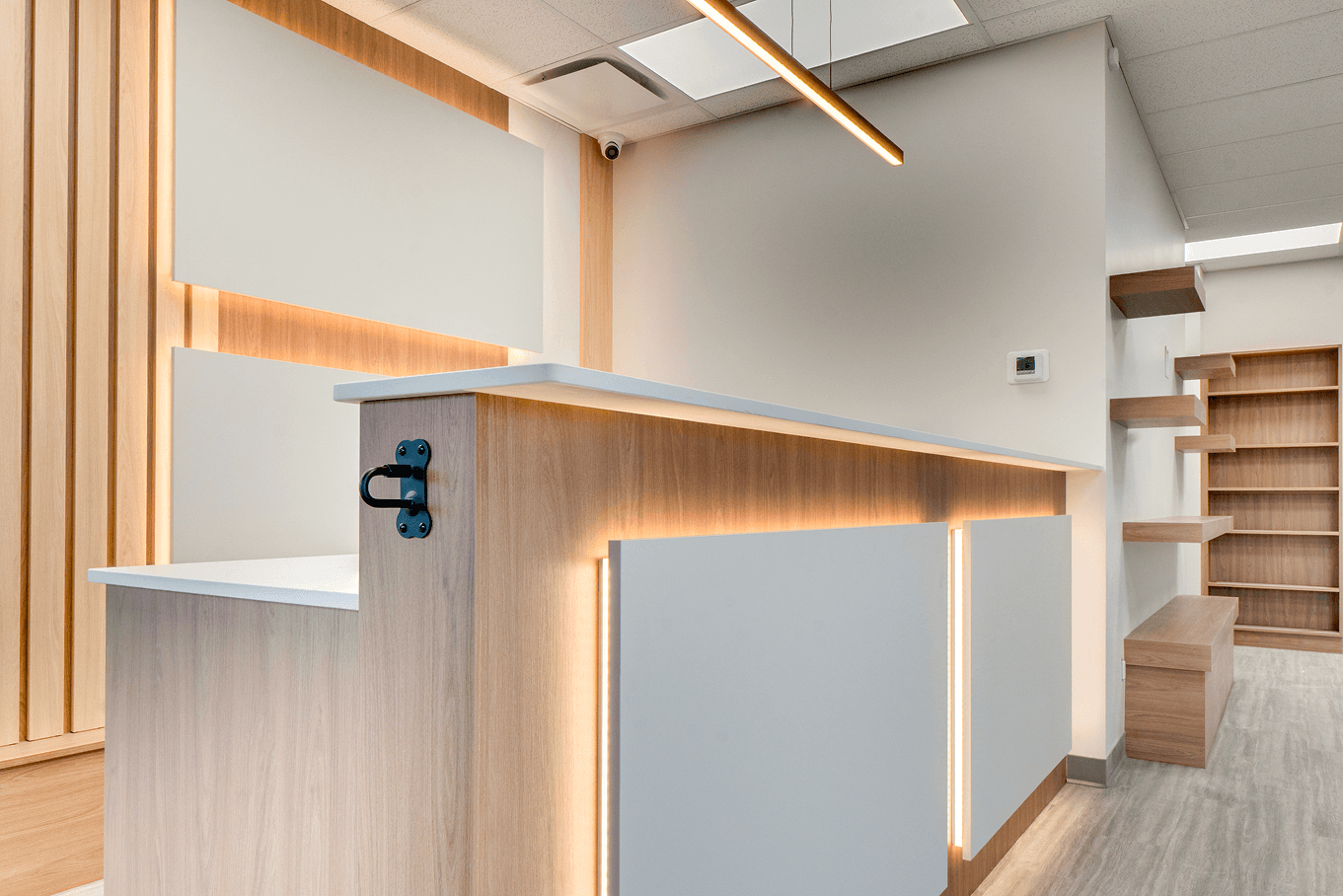 Close-up of a custom reception desk featuring wood tones, LED lighting, and clean white panel inserts.