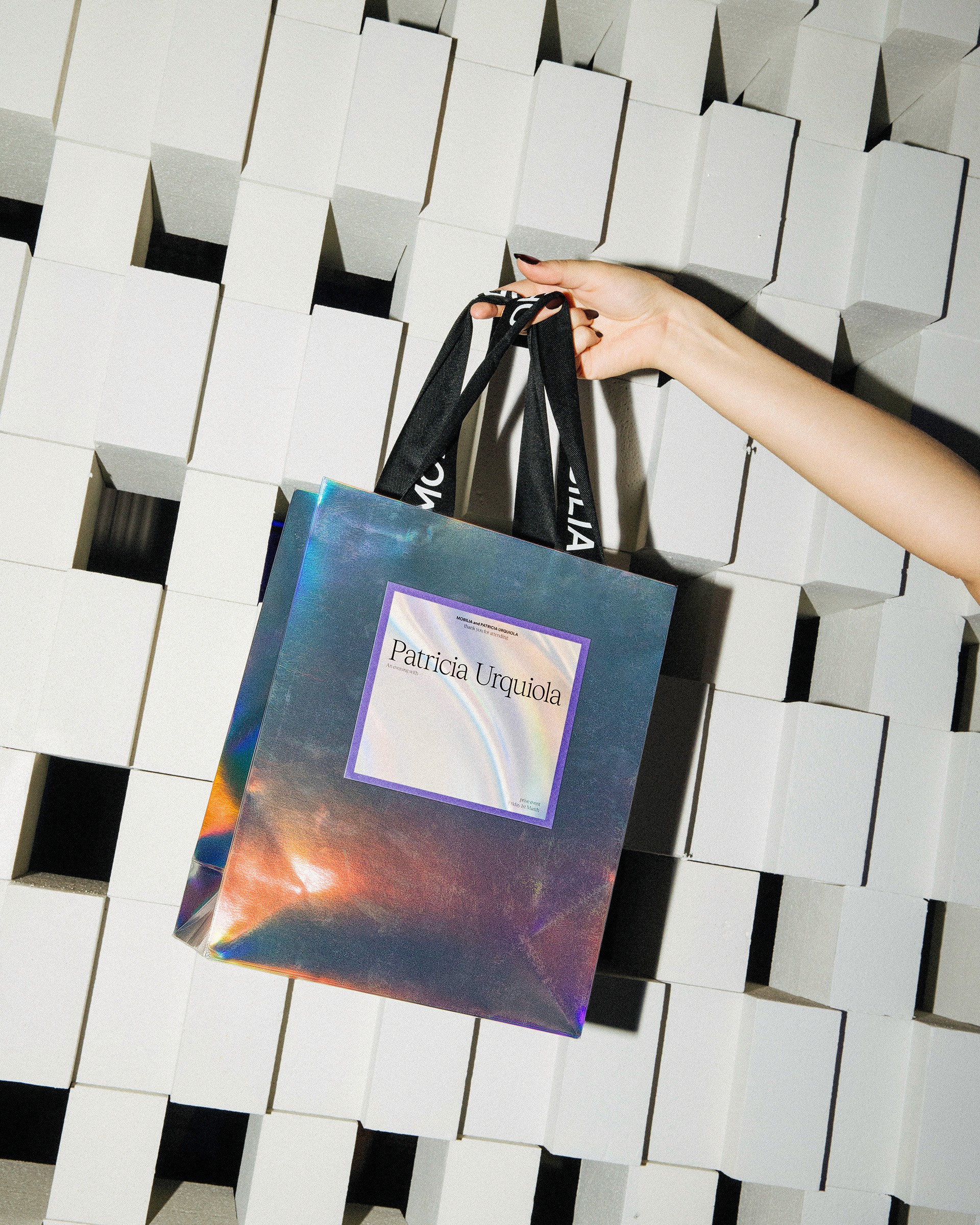 Guest holding a luxurious iridescent foil gift bag at the Mobilia VIP event, highlighting premium event branding and attention to detail in the guest experience.
