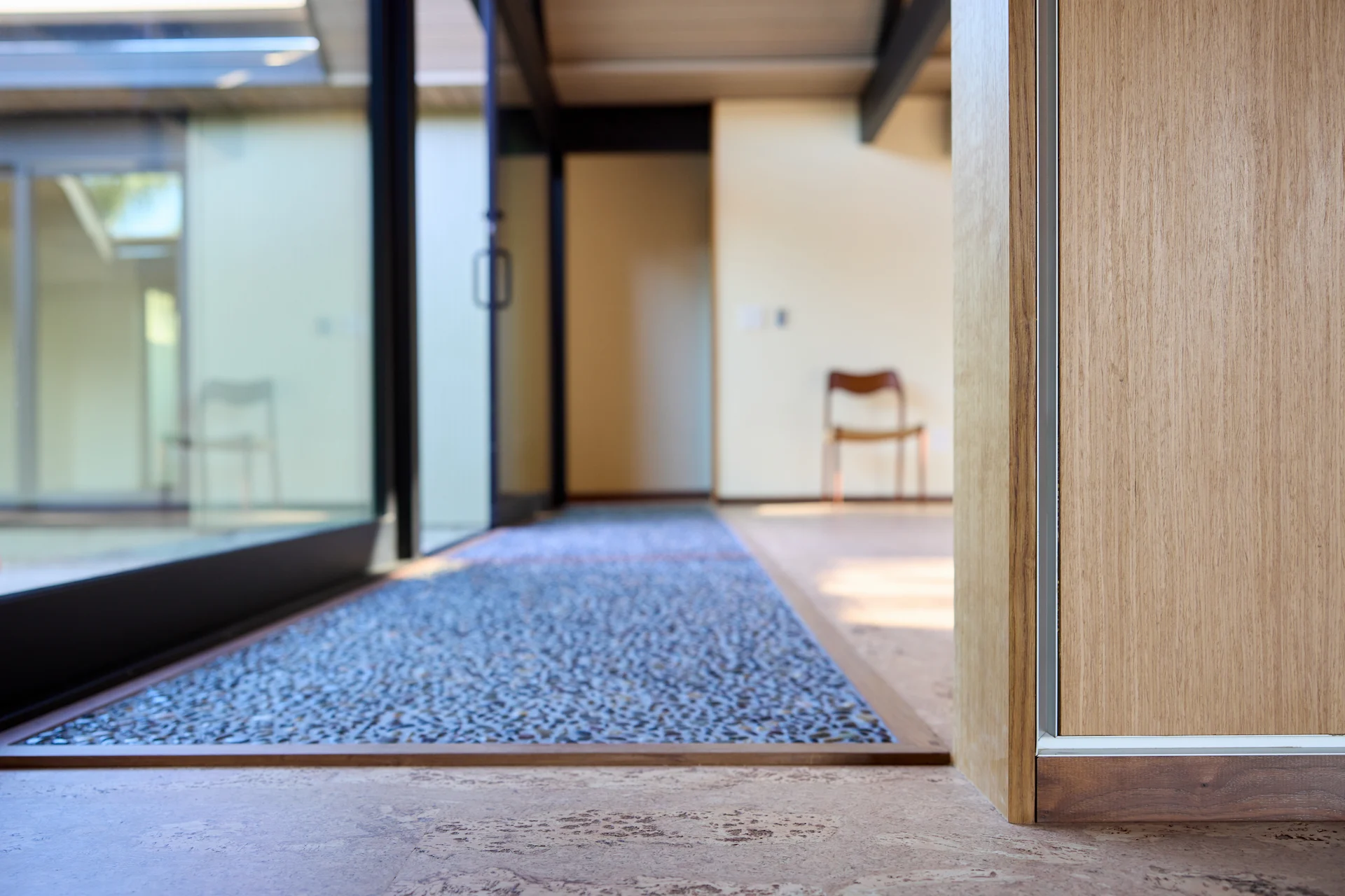 View of the living room entry featuring a meticulously crafted stone inlay, blending artistic craftsmanship with the home's modern-transitional style in the Fairhills Eichler Tract remodel. Photo by Todd Huge.