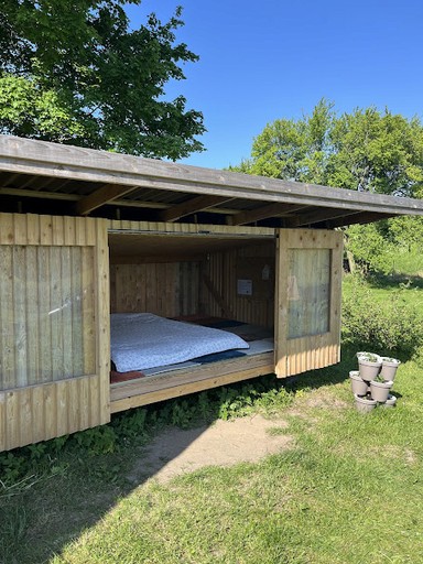 Shelteren har låger der kan åbnes og lukkes og udsigten kan nydes udover marker og køkkenhave hos Egebjerggård Grønt. 