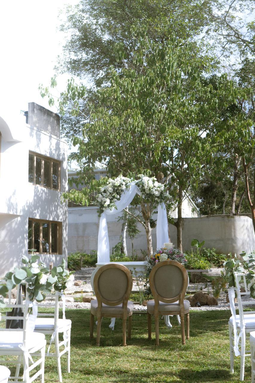 A beautifully set dining table with white tablecloth, cutlery, and fresh greenery in a cozy, well-lit space.