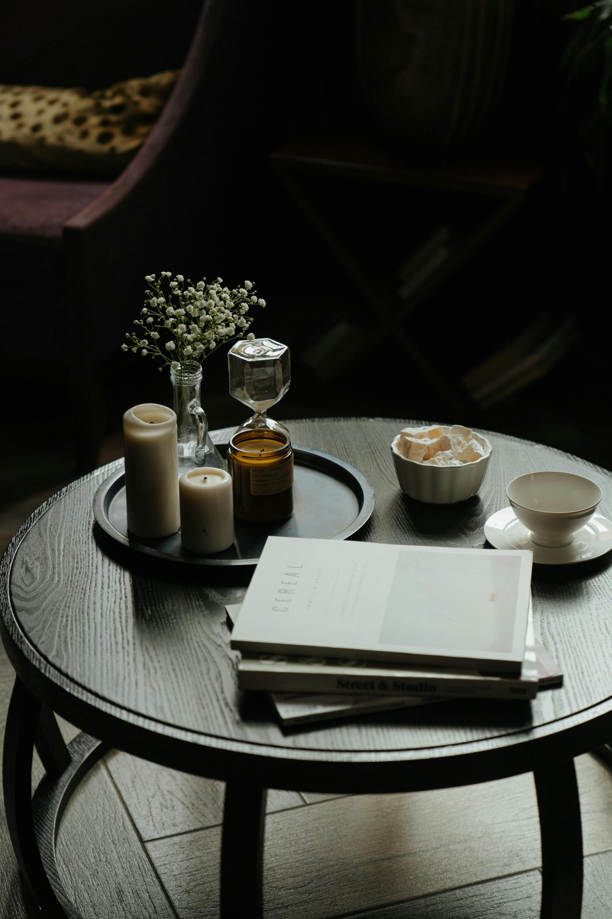 An aesthetic photo featuring a black coffee table with books, a cup, and something else placed on it.