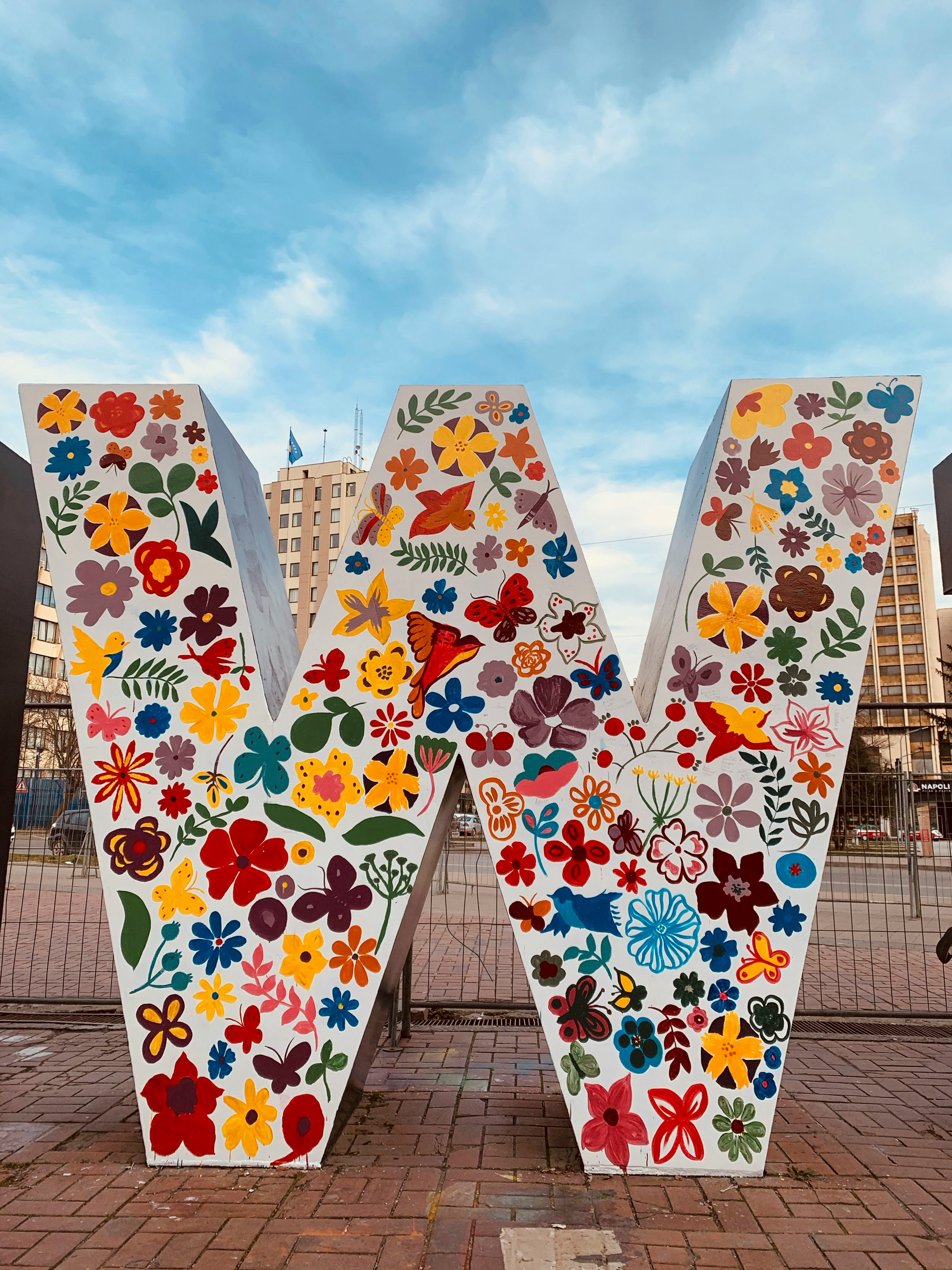 white blue and red floral textile on brown wooden fence