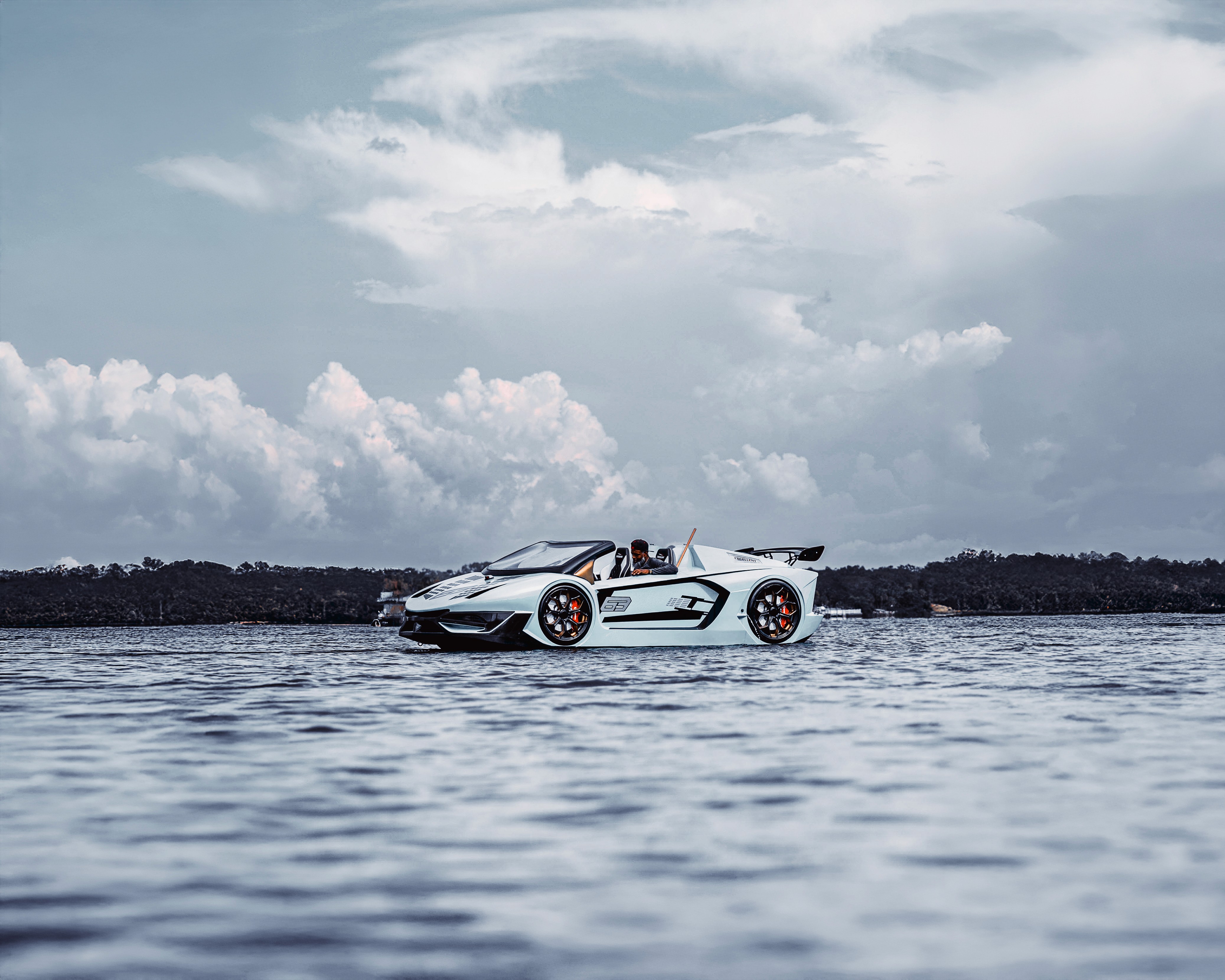 Landscape with a vineyard in rows leading to a building with a tower, rolling hills in the distance.
