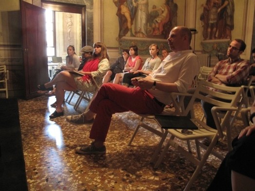 A group of people listening to a lecture and taking notes.