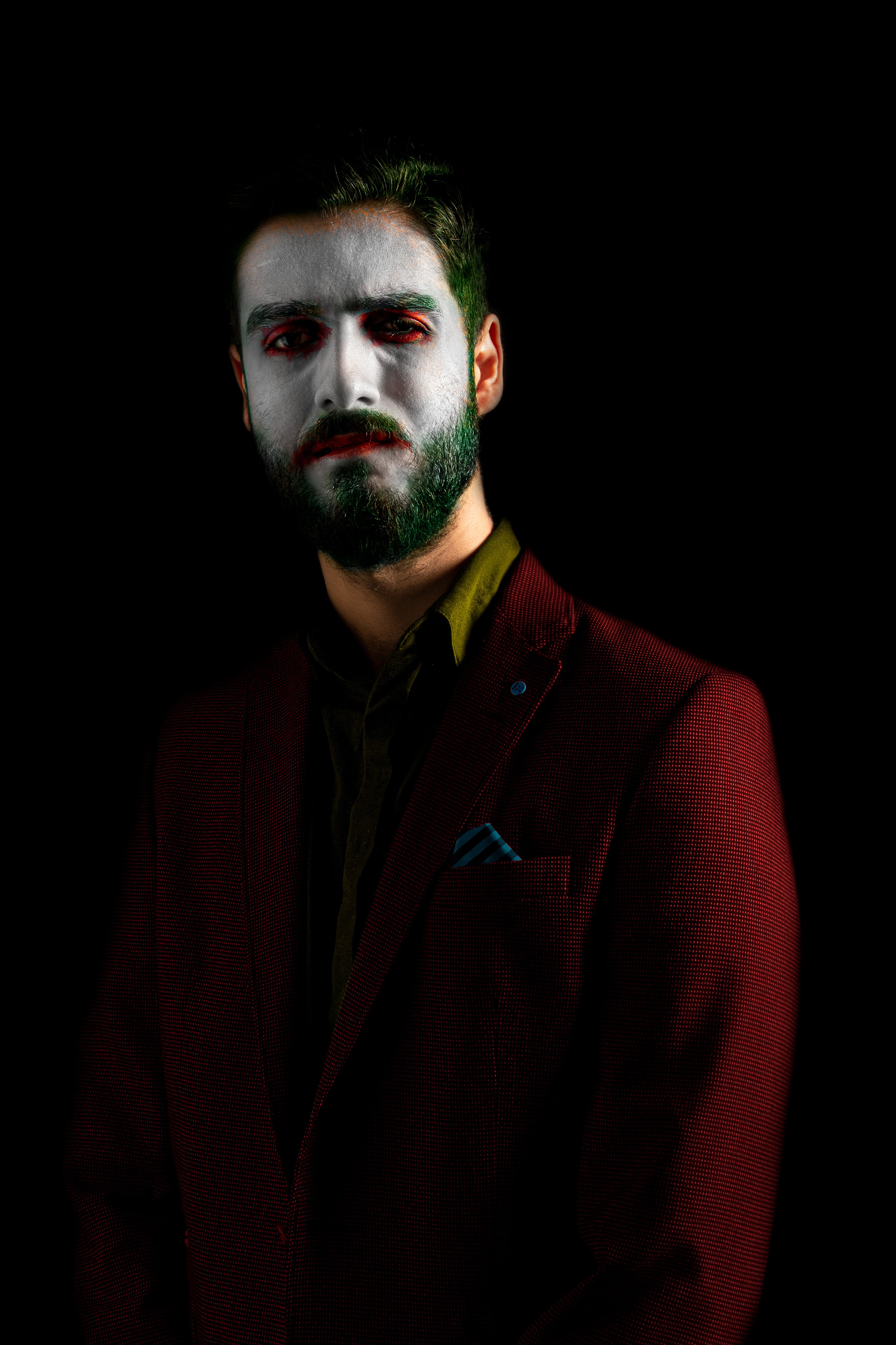Dark editorial portrait of a man in Joker-inspired makeup with a dark background