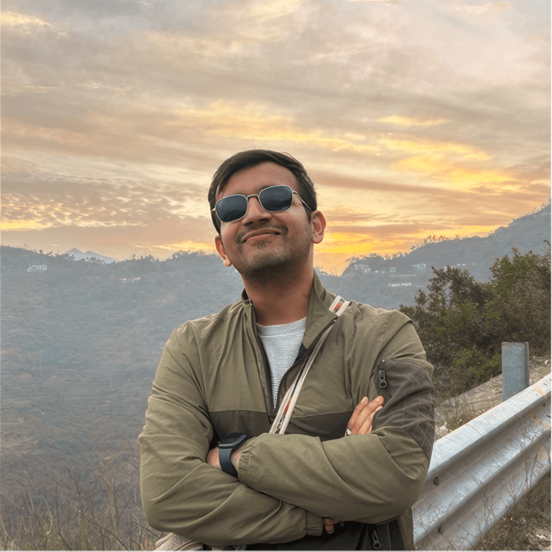 Woman with red hair and sunglasses smiling, wind-blown hair, with hot air balloons in the background.