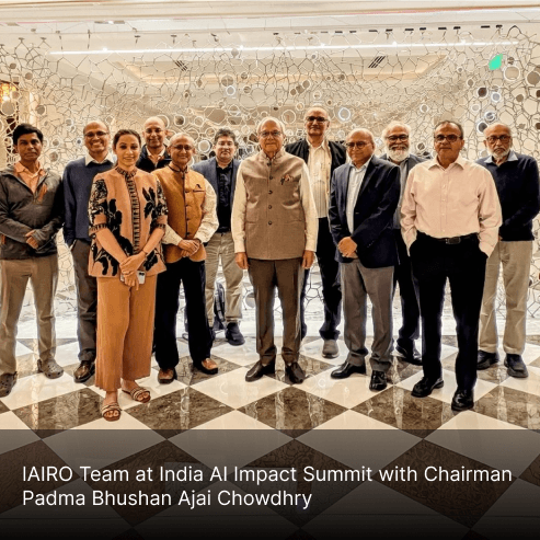 A woman with red hair and a black sleeveless top smiling confidently in a bright, modern indoor setting.