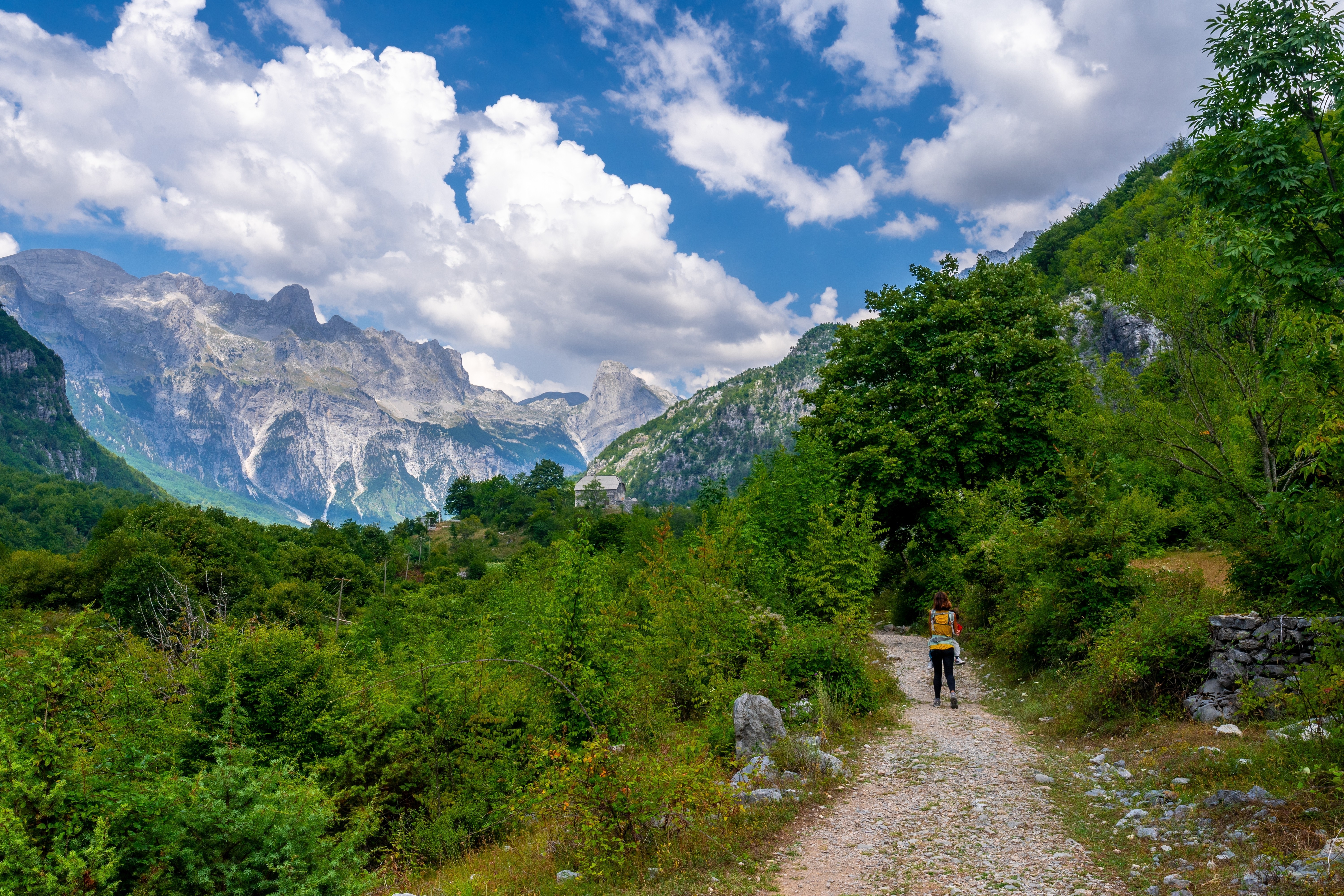 A solitary hiker walks along the path toward Grunas Waterfall in Theth National Park, Albania.