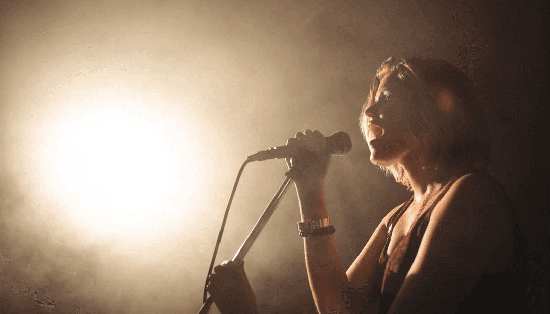This vibrant depiction of a female singer passionately performing under intense spotlight on a dim lit stage captures the essence of live music and vibrant nightlife.