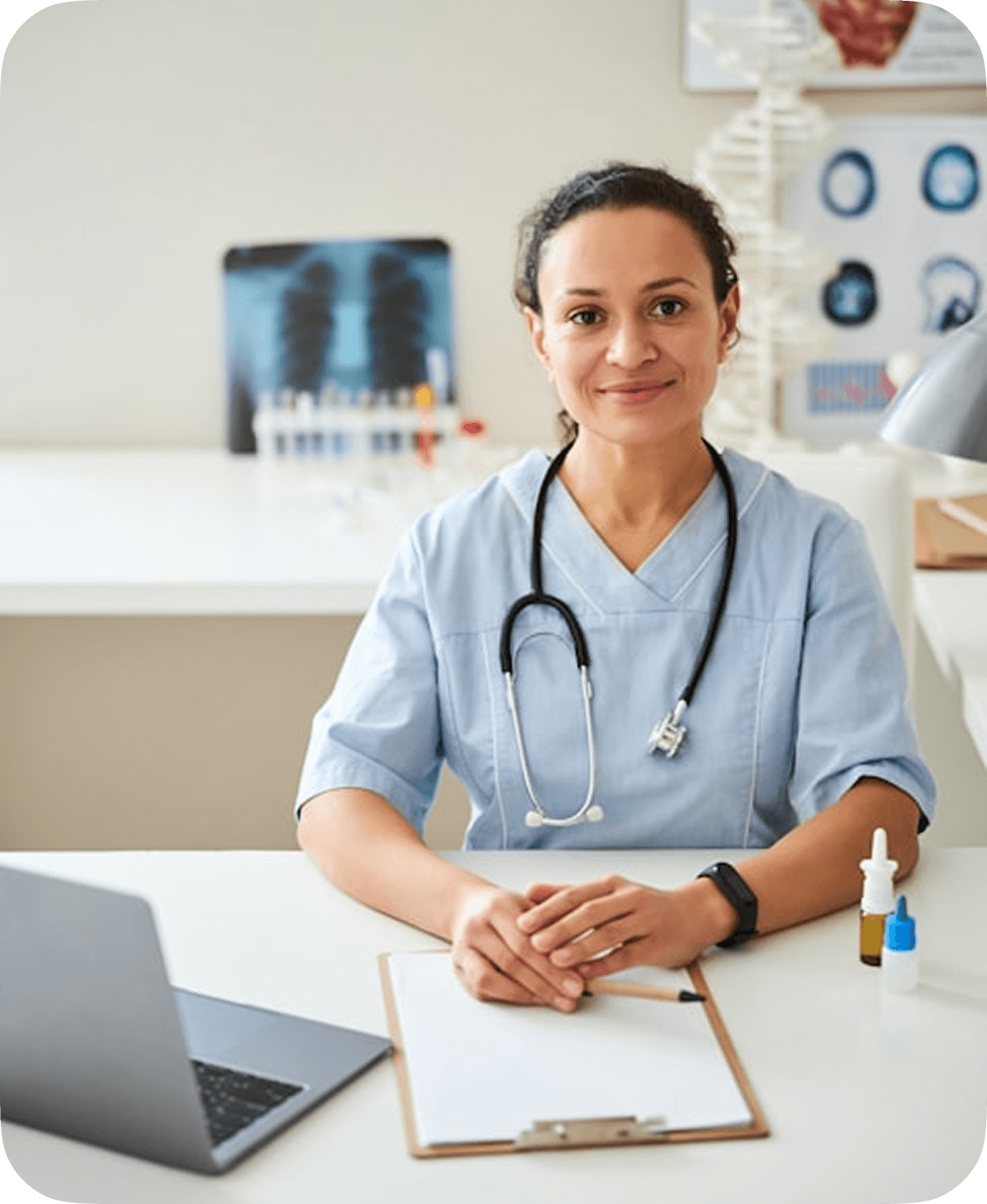 A healthcare professional in a blue uniform sits at a desk with a laptop, clipboard, and medical supplies, surrounded by anatomical charts and a model skeleton in a medical office setting.