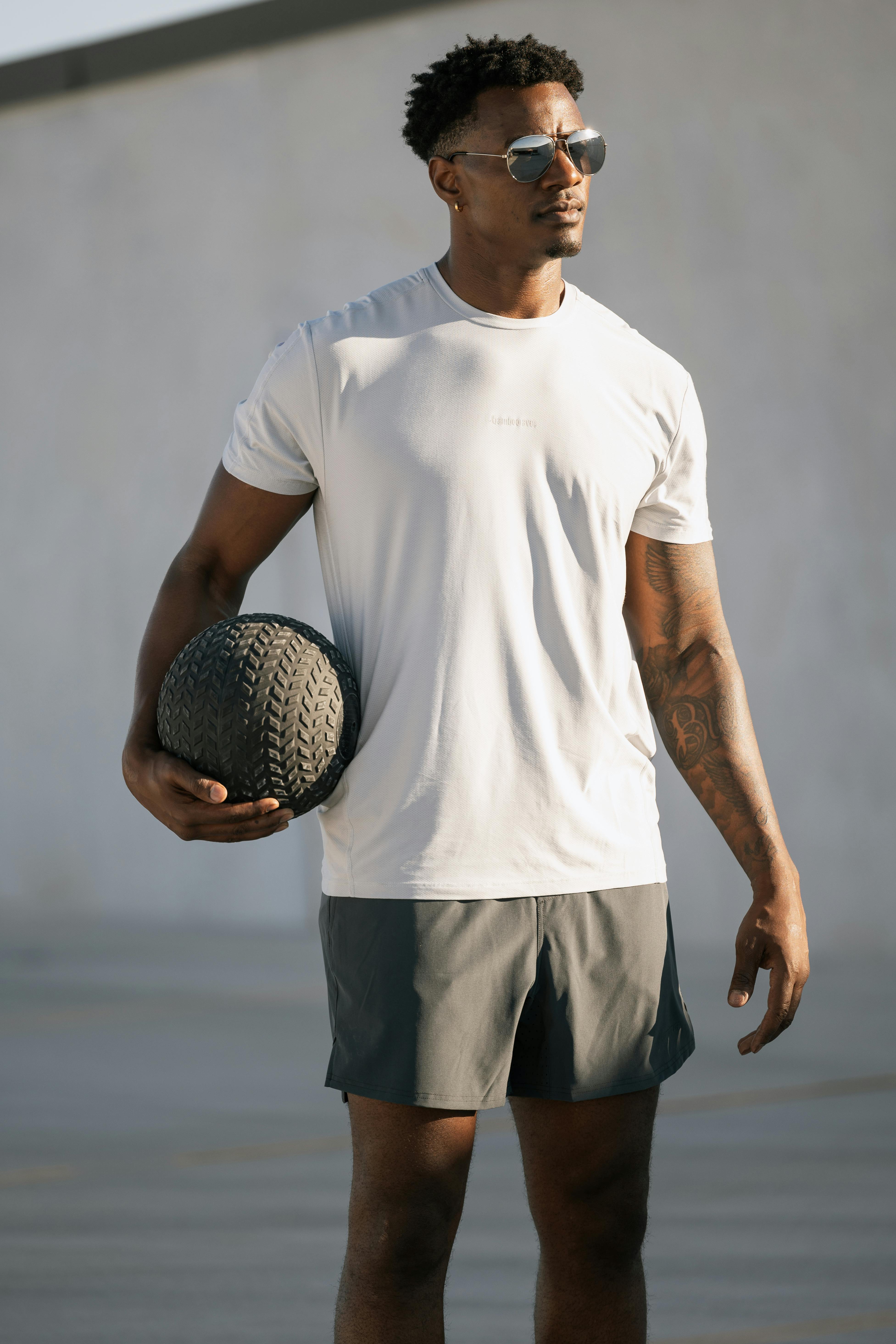 Man holding a ball in a sports outfit in a sunny environment.